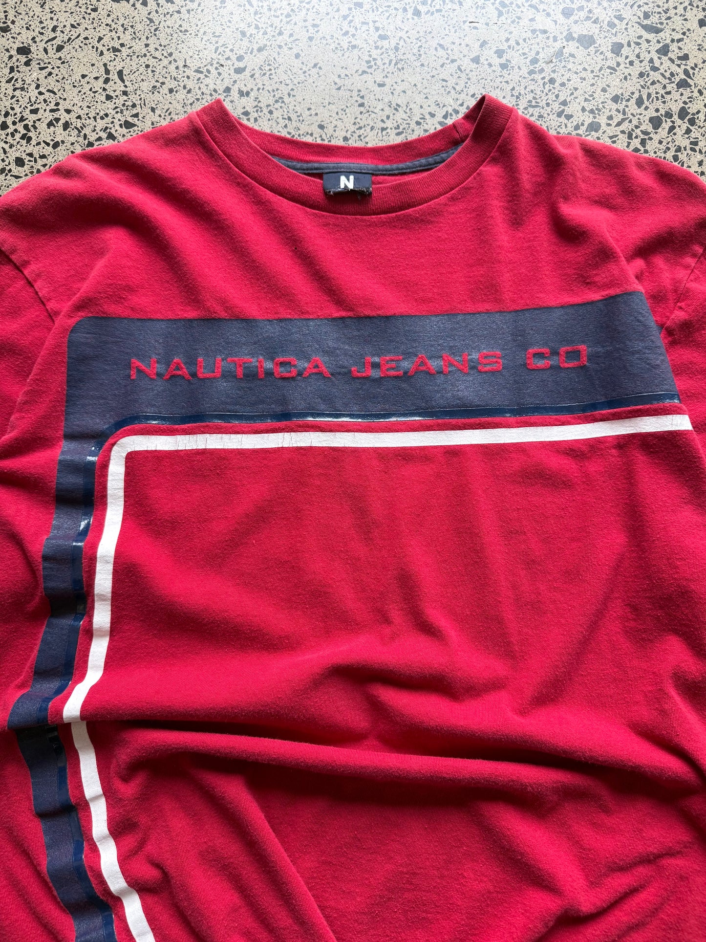 2000s Nautica long sleeve T-shirt, navy, size L, laid on polished concrete background — subtle Y2K branding on soft cotton.