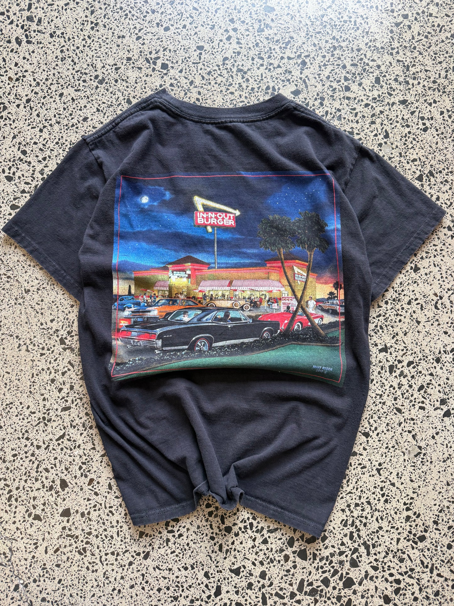 In-N-Out graphic T-shirt, size S, laid on polished concrete background — soft cotton with bold front logo print.