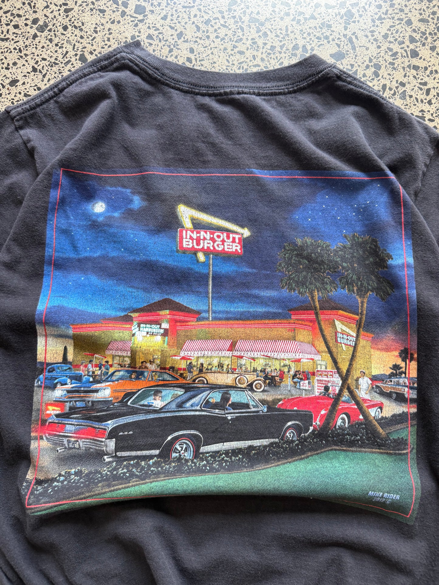 In-N-Out graphic T-shirt, size S, laid on polished concrete background — soft cotton with bold front logo print.