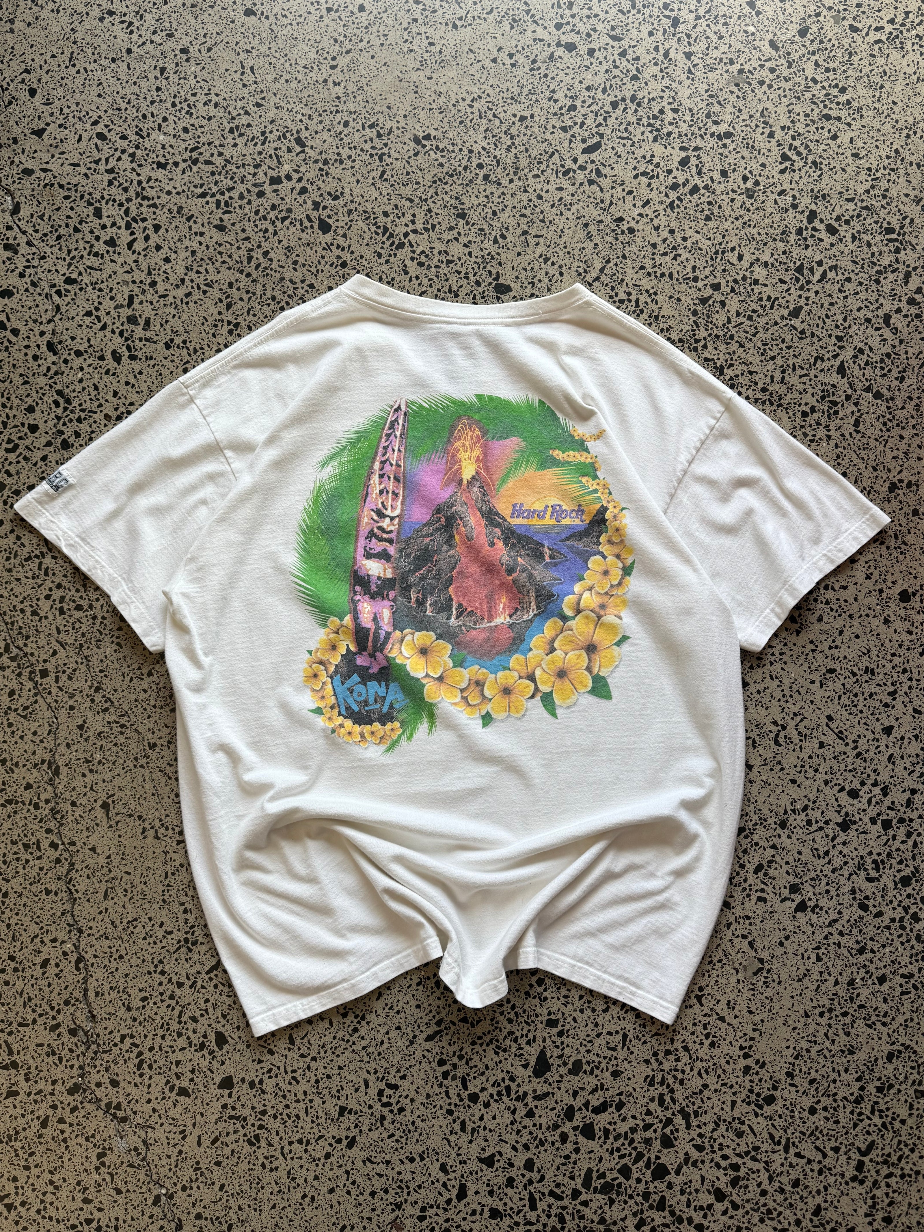 White 80s Hard Rock Kona graphic t-shirt with multicoloured print, size XL, laid flat on a polished concrete background