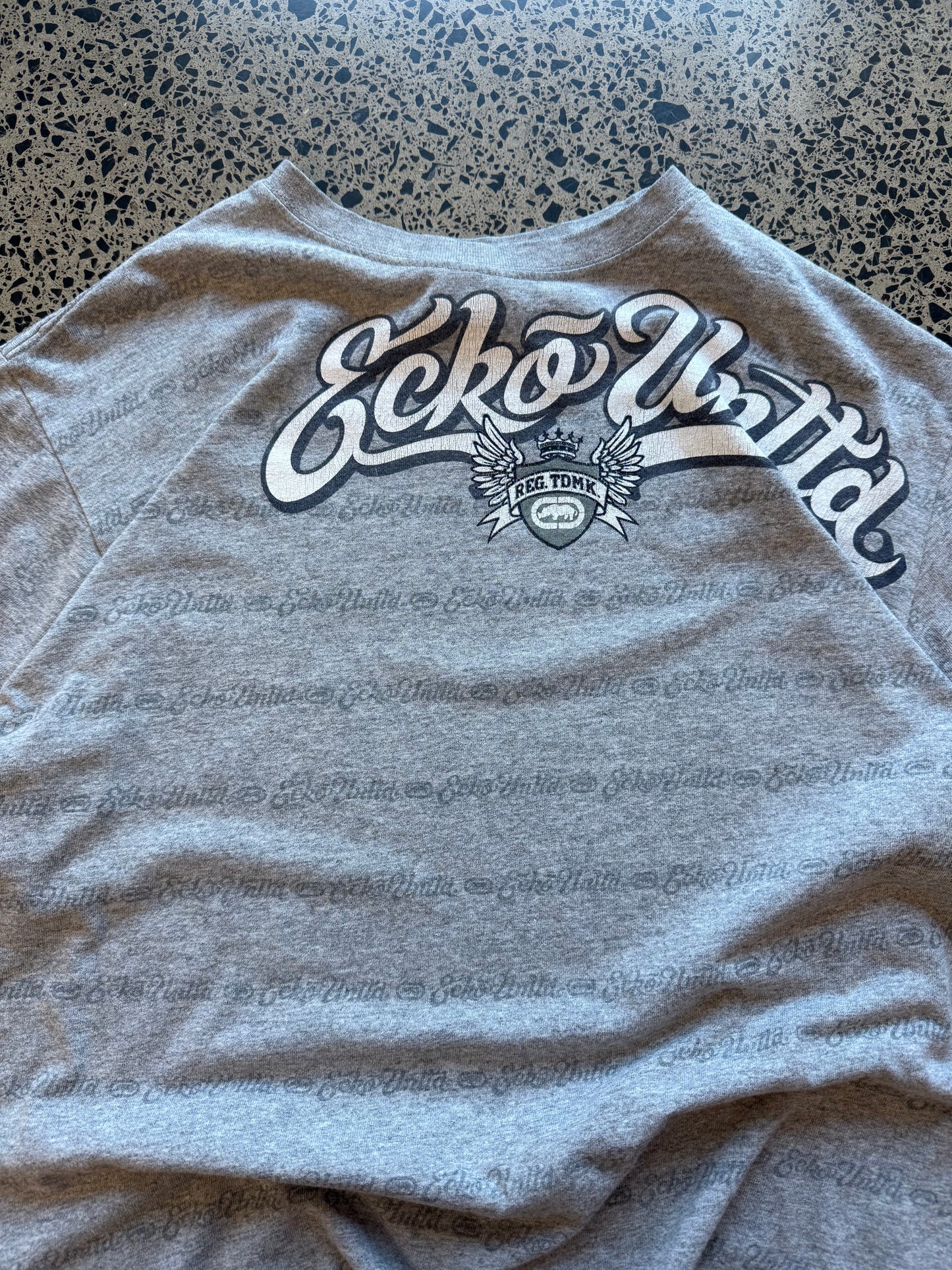 Grey Y2K Ecko Unltd graphic t-shirt with bold chest print, size M, laid flat on a polished concrete background