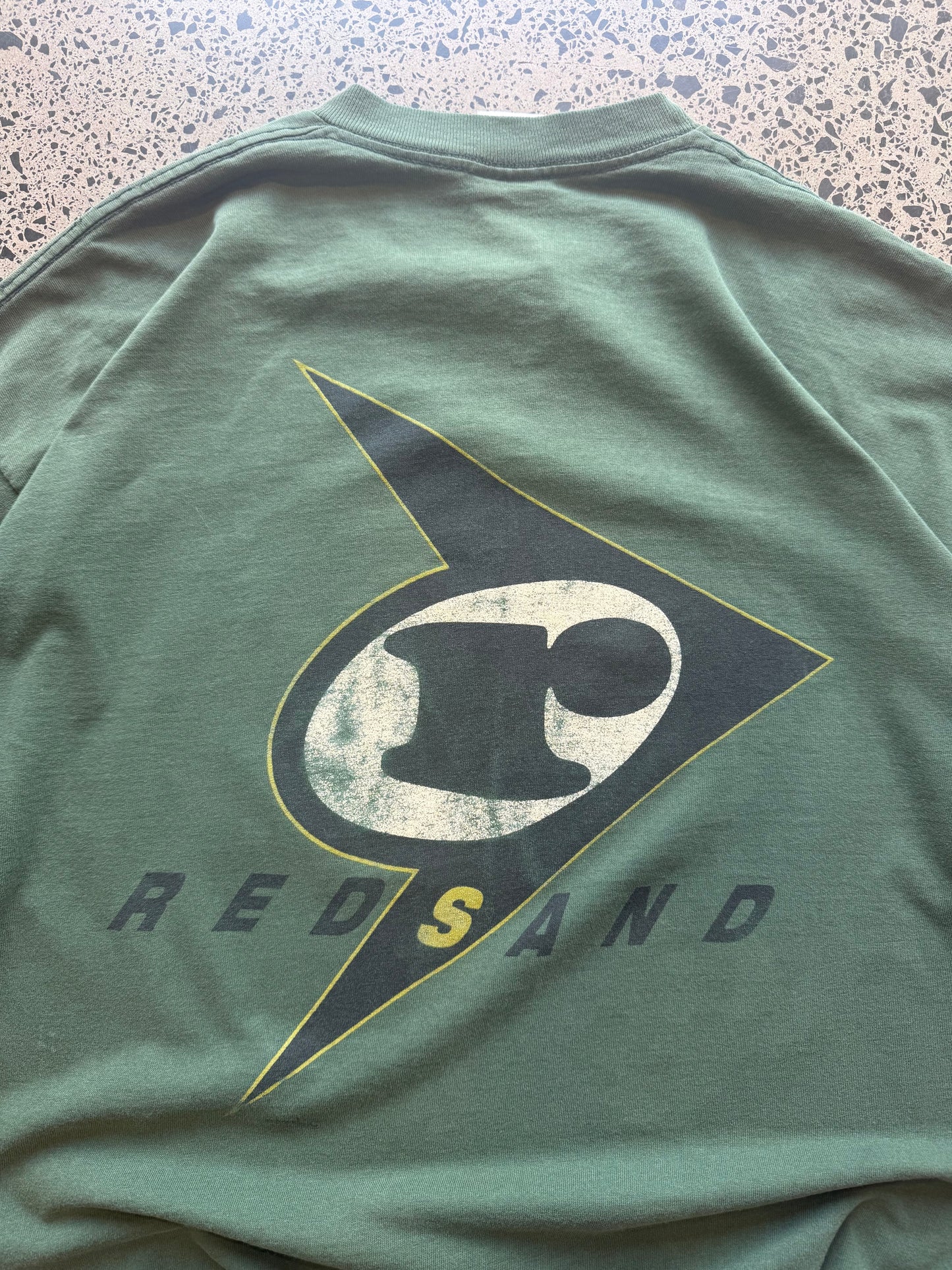 90s Red Sand surf graphic T-shirt, size XL, laid on polished concrete background — vintage beach graphic on soft cotton.