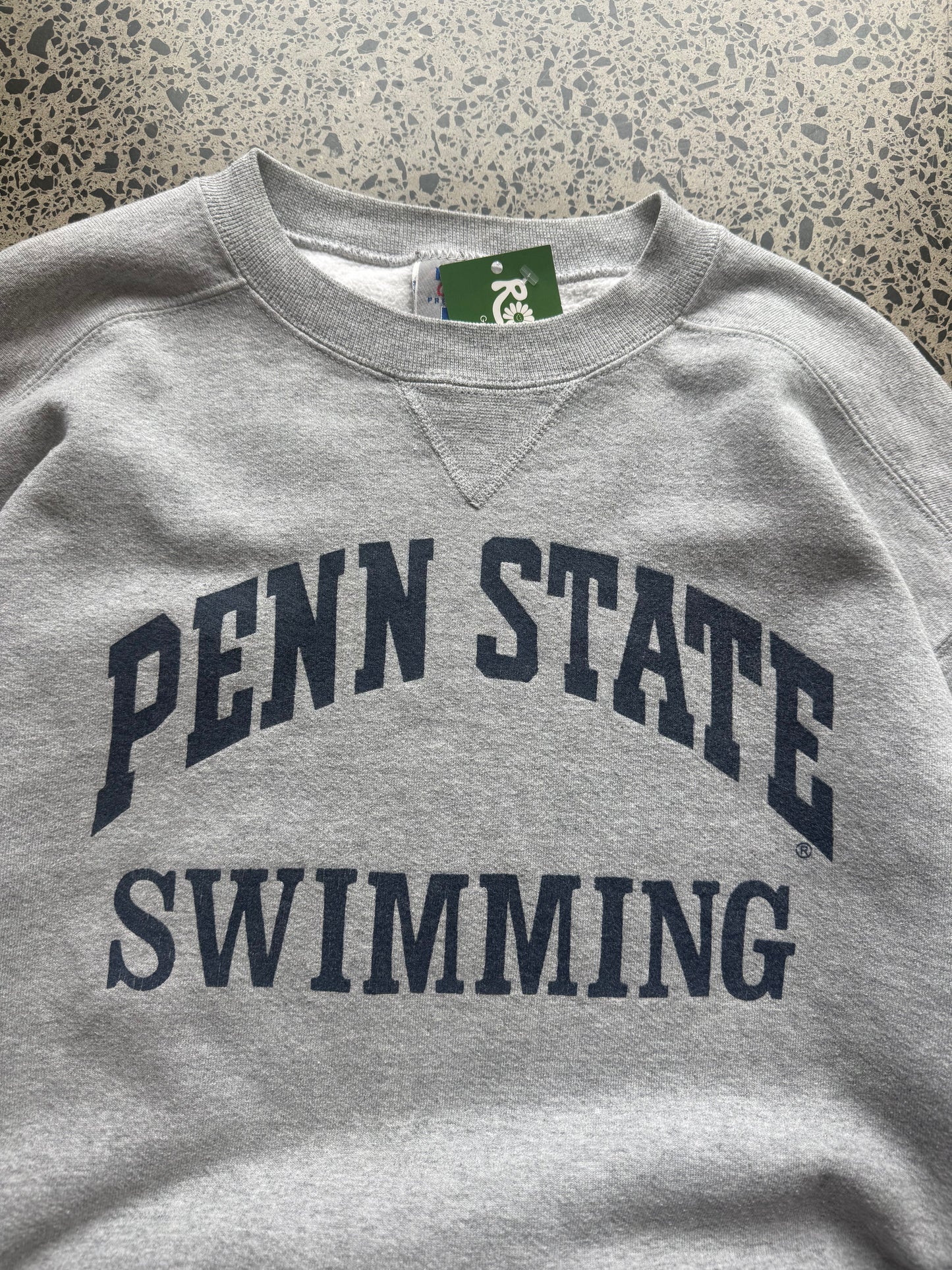 90s Penn State University crewneck jumper size M laid flat on polished concrete background, vintage college sweatshirt with bold lettering and classic fit.