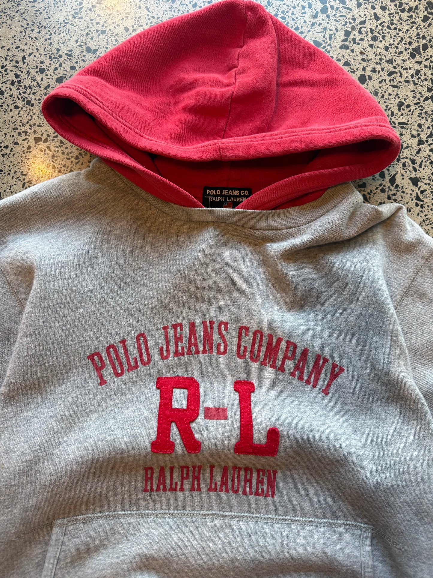 90s Ralph Lauren two-tone hoodie youth size L 10–12 laid flat on polished concrete background, vintage kids hoodie with colour block design and classic Ralph Lauren styling.