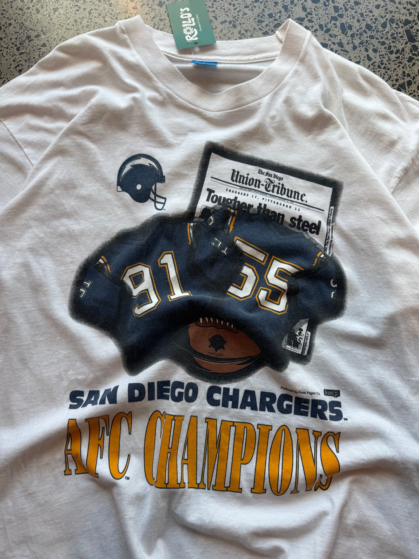 90s San Diego Chargers American Football T-shirt, size XL, laid on polished concrete background, bold vintage NFL graphic on soft cotton.