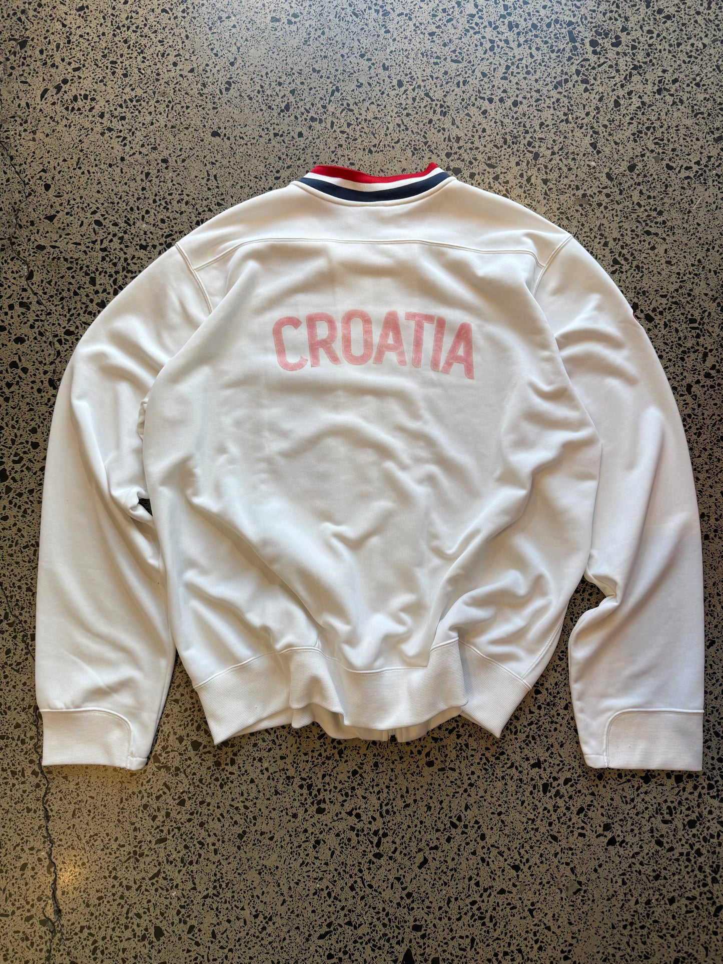 Croatia Nike red and white zip-up football jumper, size XXL, laid on polished concrete background — ¼-zip pullover with team crest and swoosh.