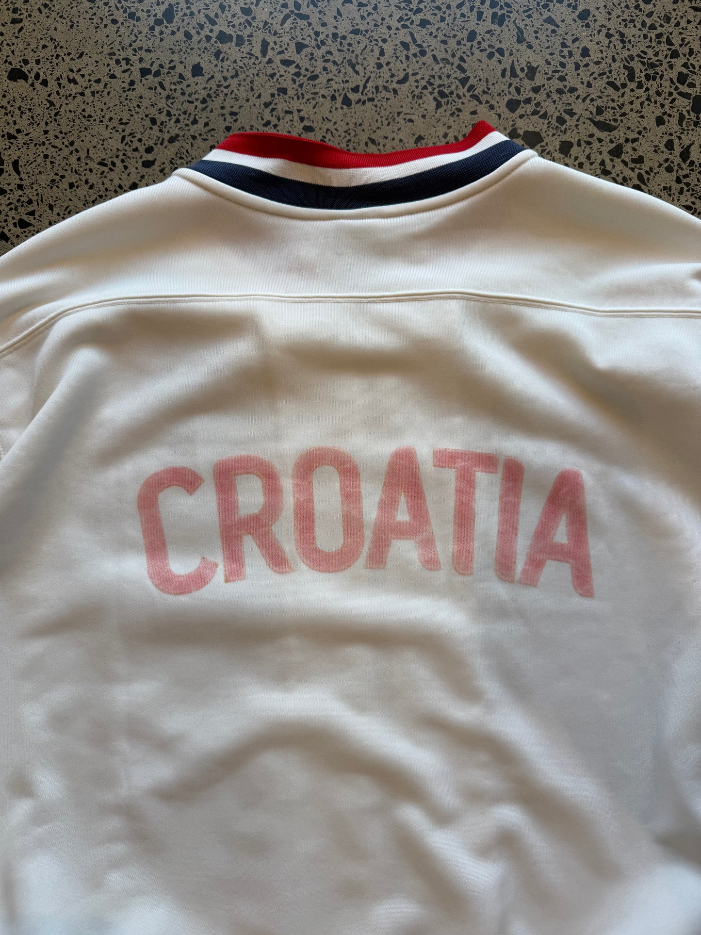 Croatia Nike red and white zip-up football jumper, size XXL, laid on polished concrete background — ¼-zip pullover with team crest and swoosh.