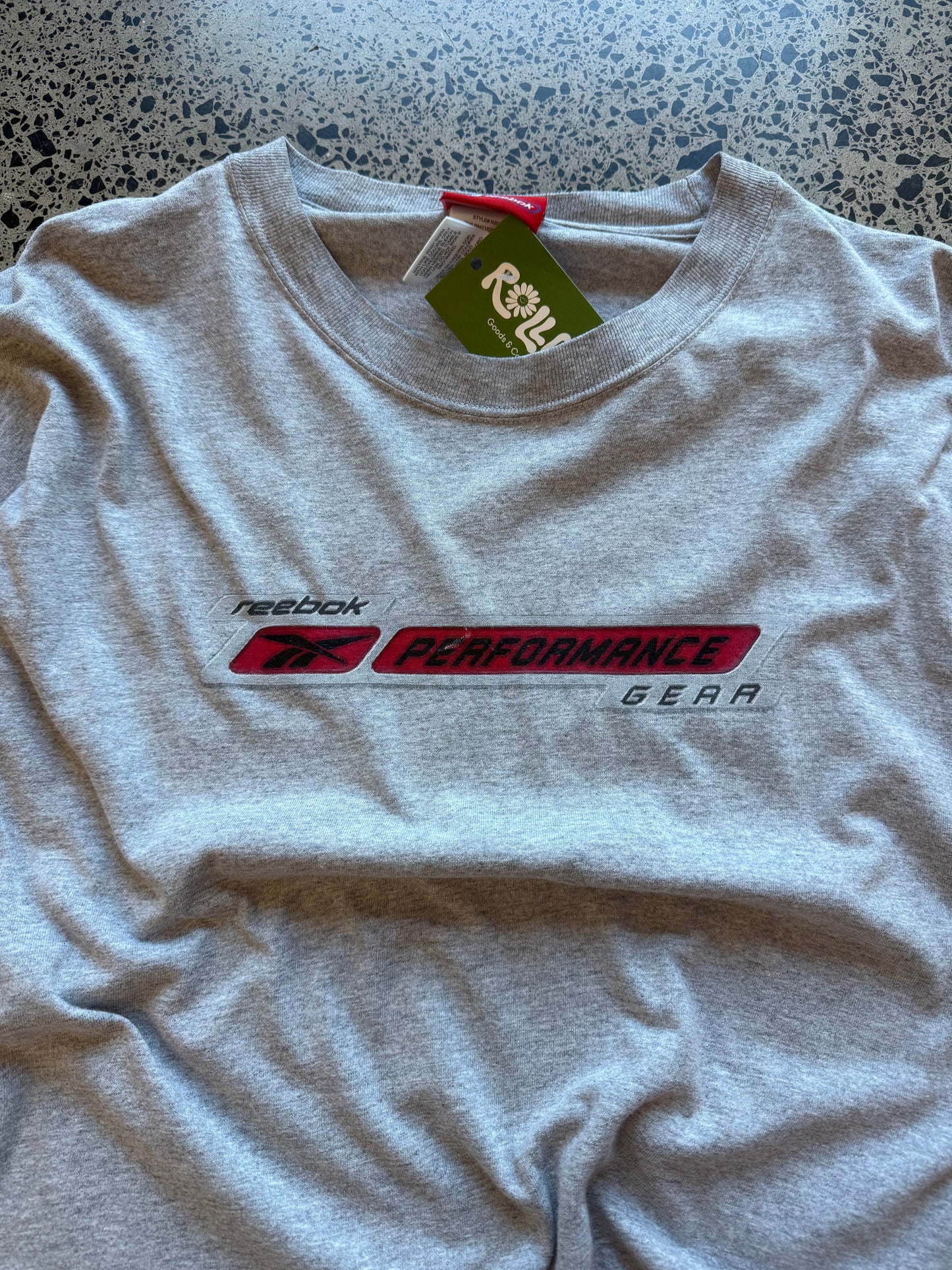 Early 2000s Reebok long sleeve T-shirt size L laid on polished concrete background — black with bold Reebok logo.