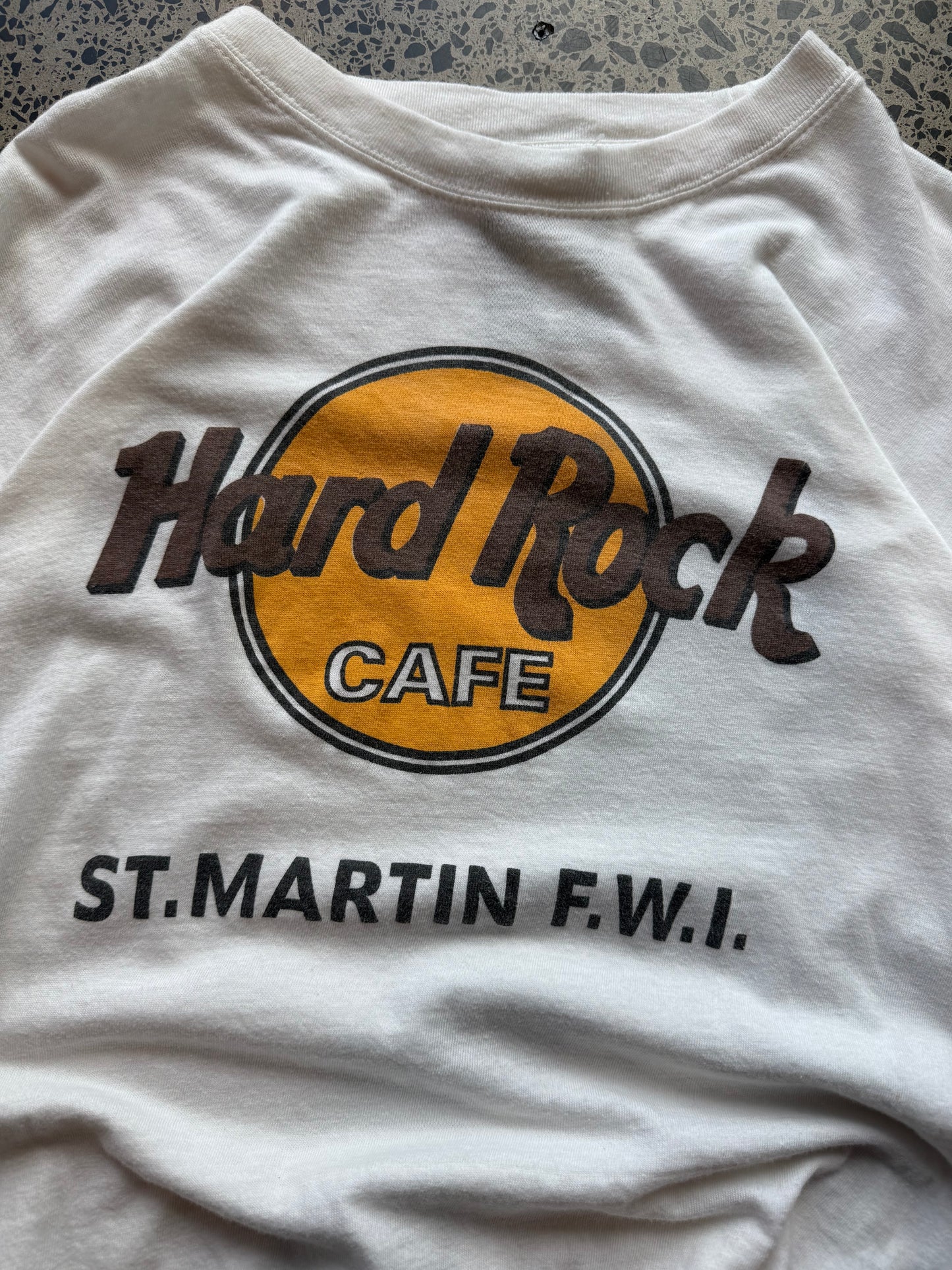 Hard Rock St. Martin graphic T-shirt, size L, laid on polished concrete background — classic Hard Rock logo on soft cotton.