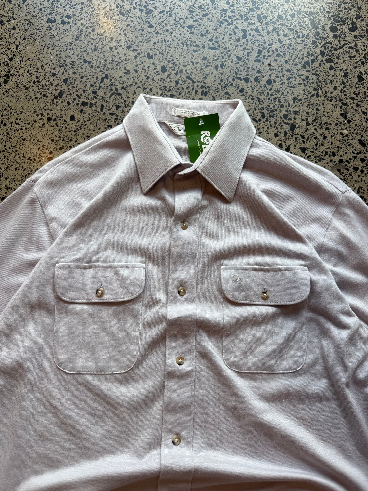 Late 80s early 90s Dior button-up shirt in size L laid flat on a polished concrete background featuring classic vintage designer tailoring.