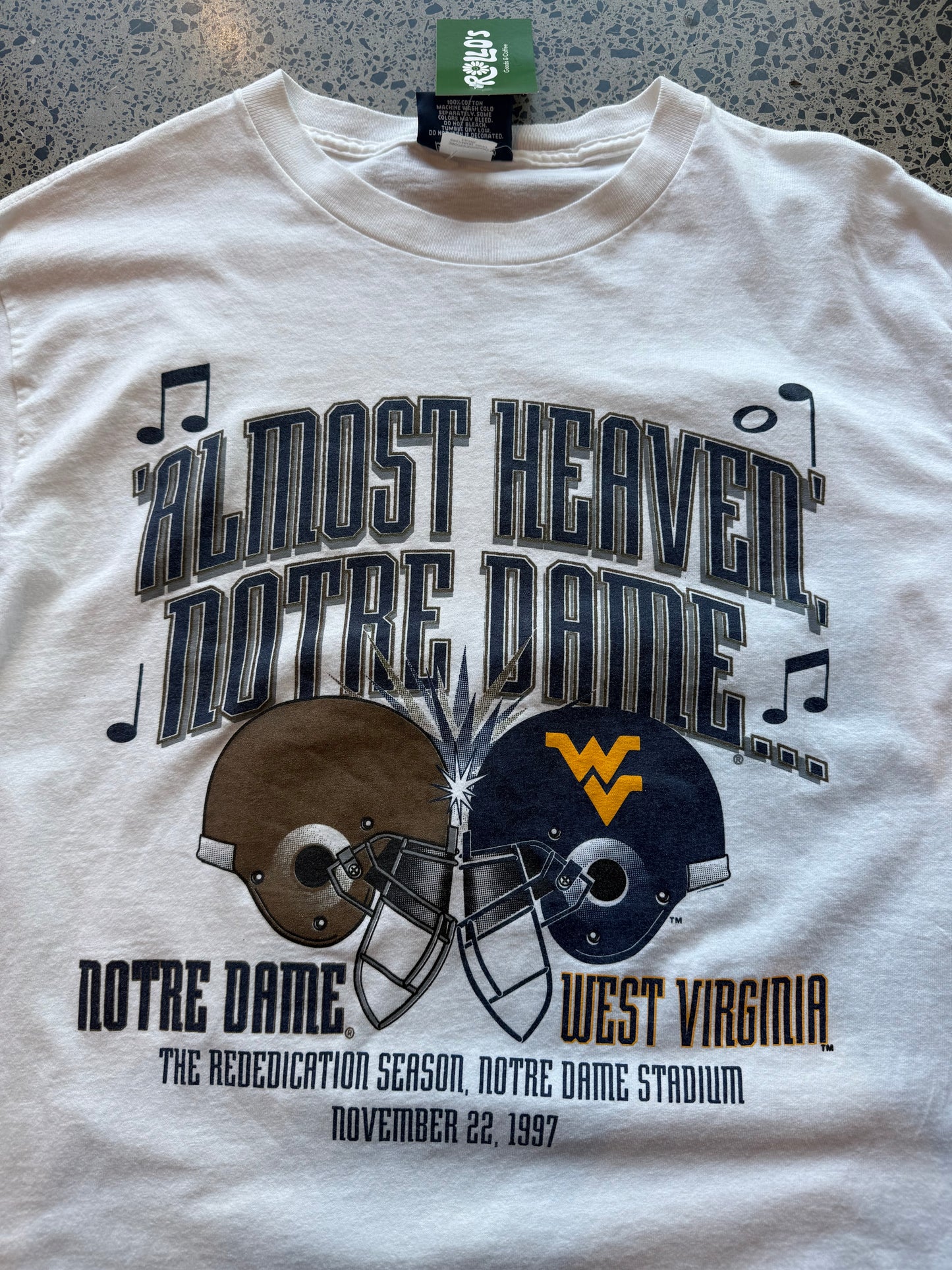 1997 Notre Dame American Football T-shirt, size L, made in USA, laid on polished concrete background — vintage collegiate football graphic on soft cotton.