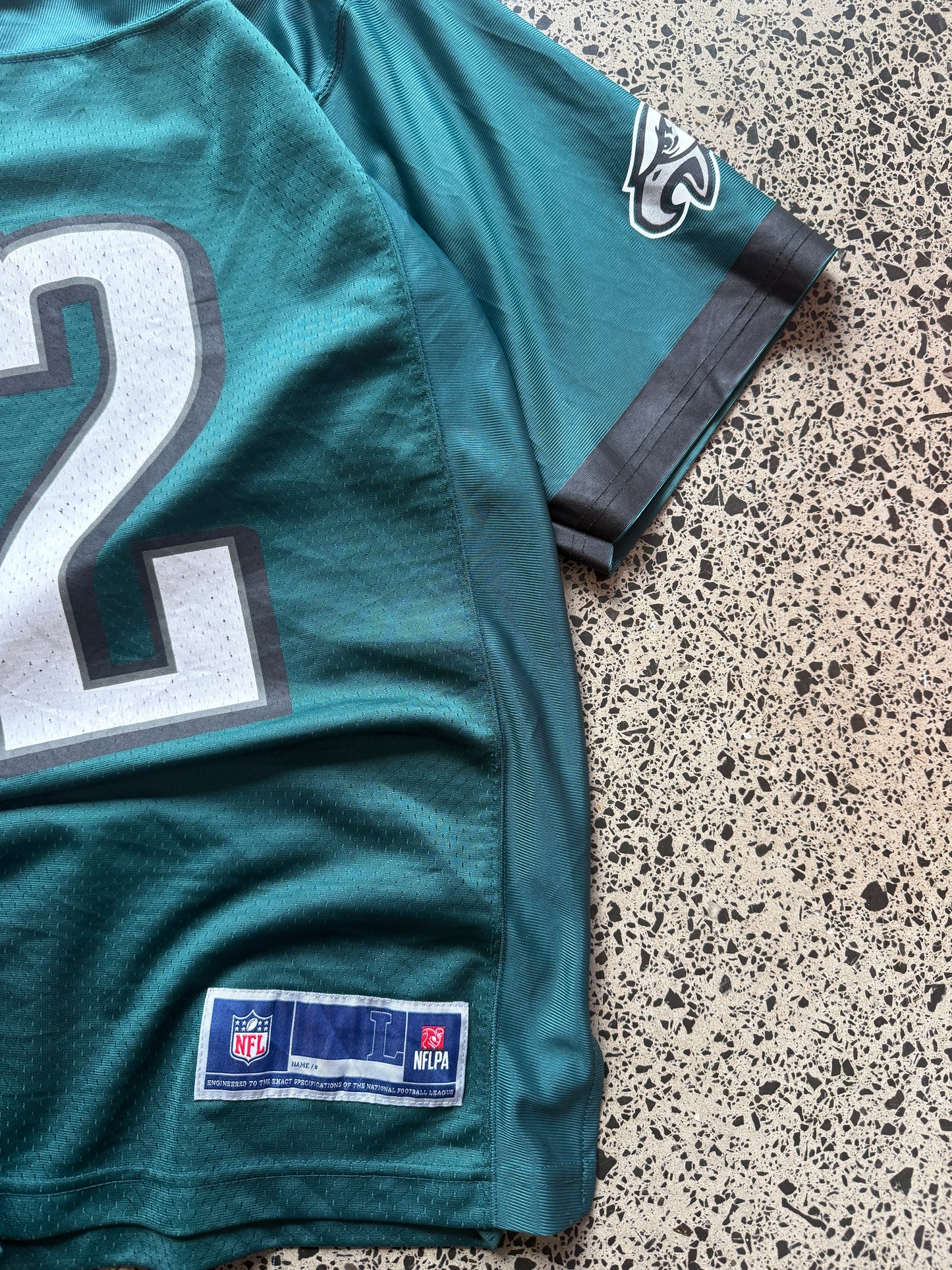 Philadelphia Eagles Halapoulivaati Vaitai NFL jersey size L laid on polished concrete background — midnight green with white detailing and Eagles logo.