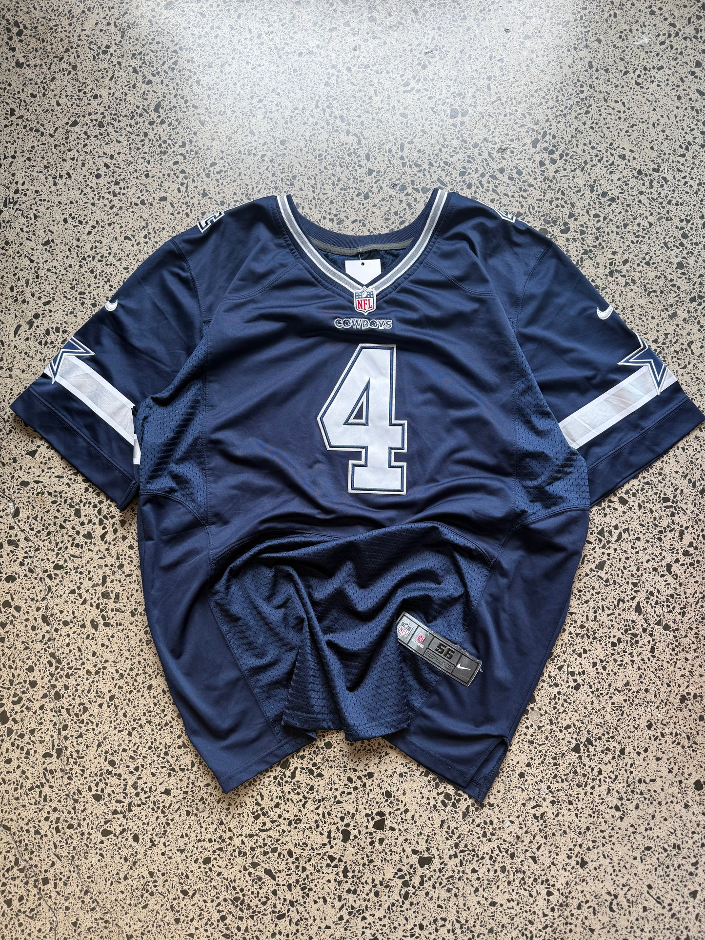 Dallas Cowboys Dak Prescott NFL jersey size 3XL laid on polished concrete background — navy with white detailing and star logo.