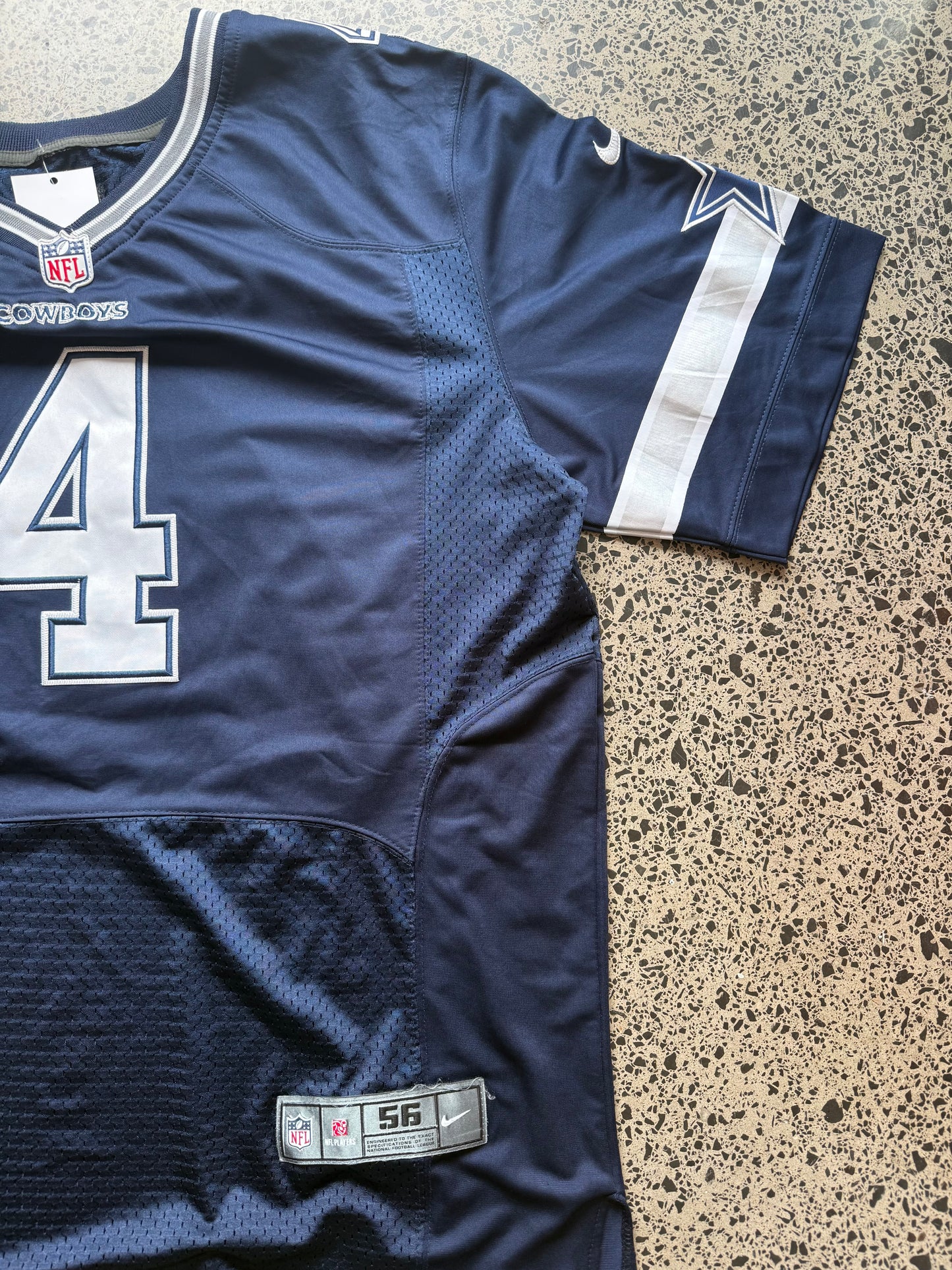 Dallas Cowboys Dak Prescott NFL jersey size 3XL laid on polished concrete background — navy with white detailing and star logo.