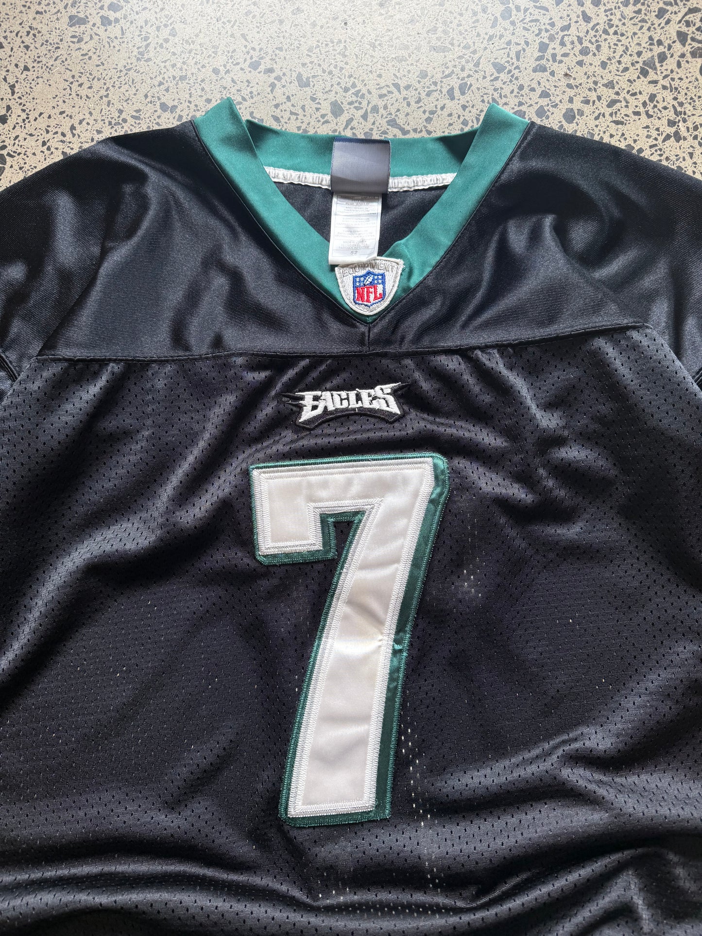 Philadelphia Eagles Michael Vick NFL jersey size 2XL laid on polished concrete background — midnight green with white detailing and Eagles logo.