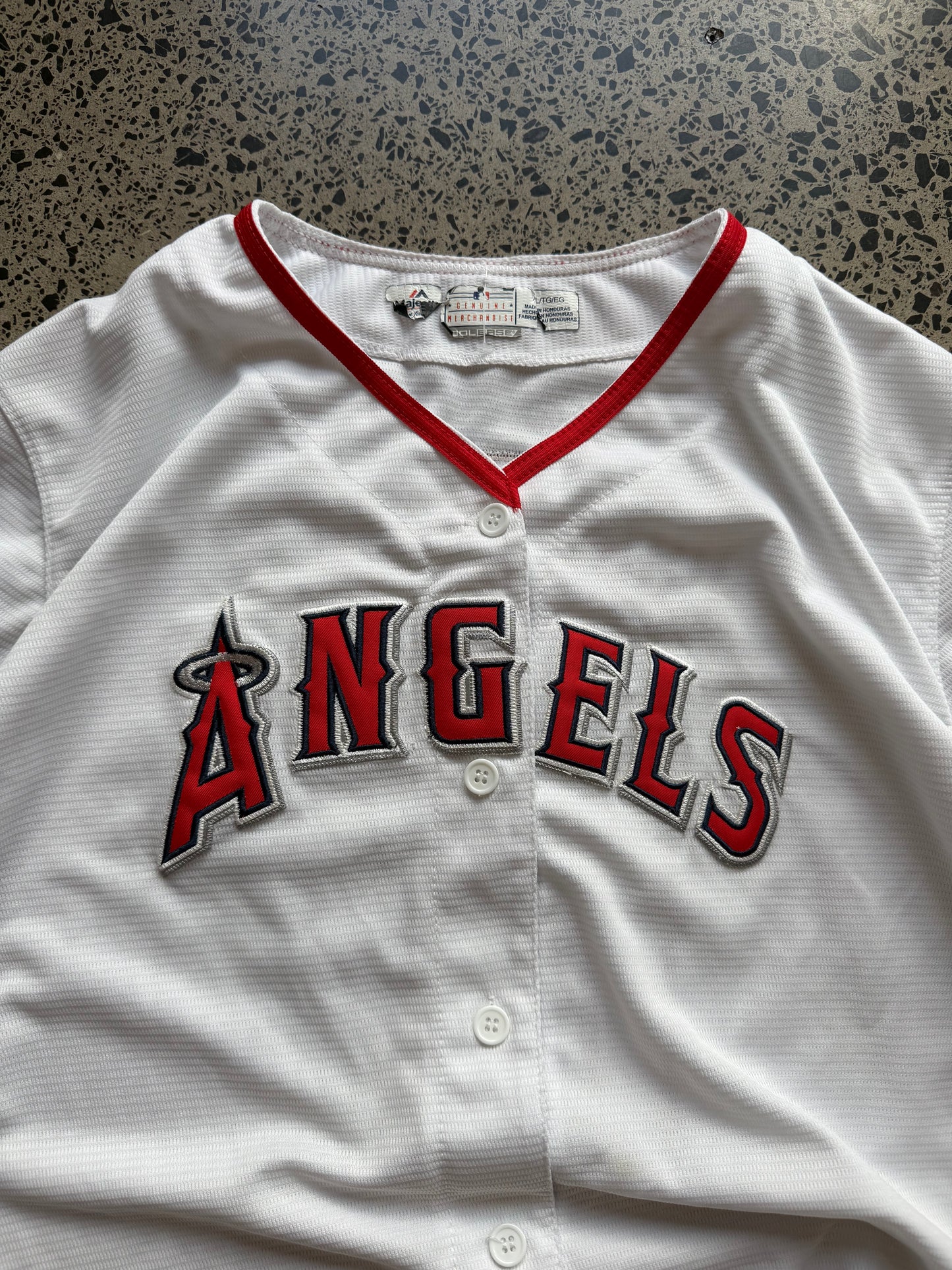 LA Angels Shohei Ohtani MLB baseball jersey size XL laid on polished concrete background — red with white detailing and Angels logo.