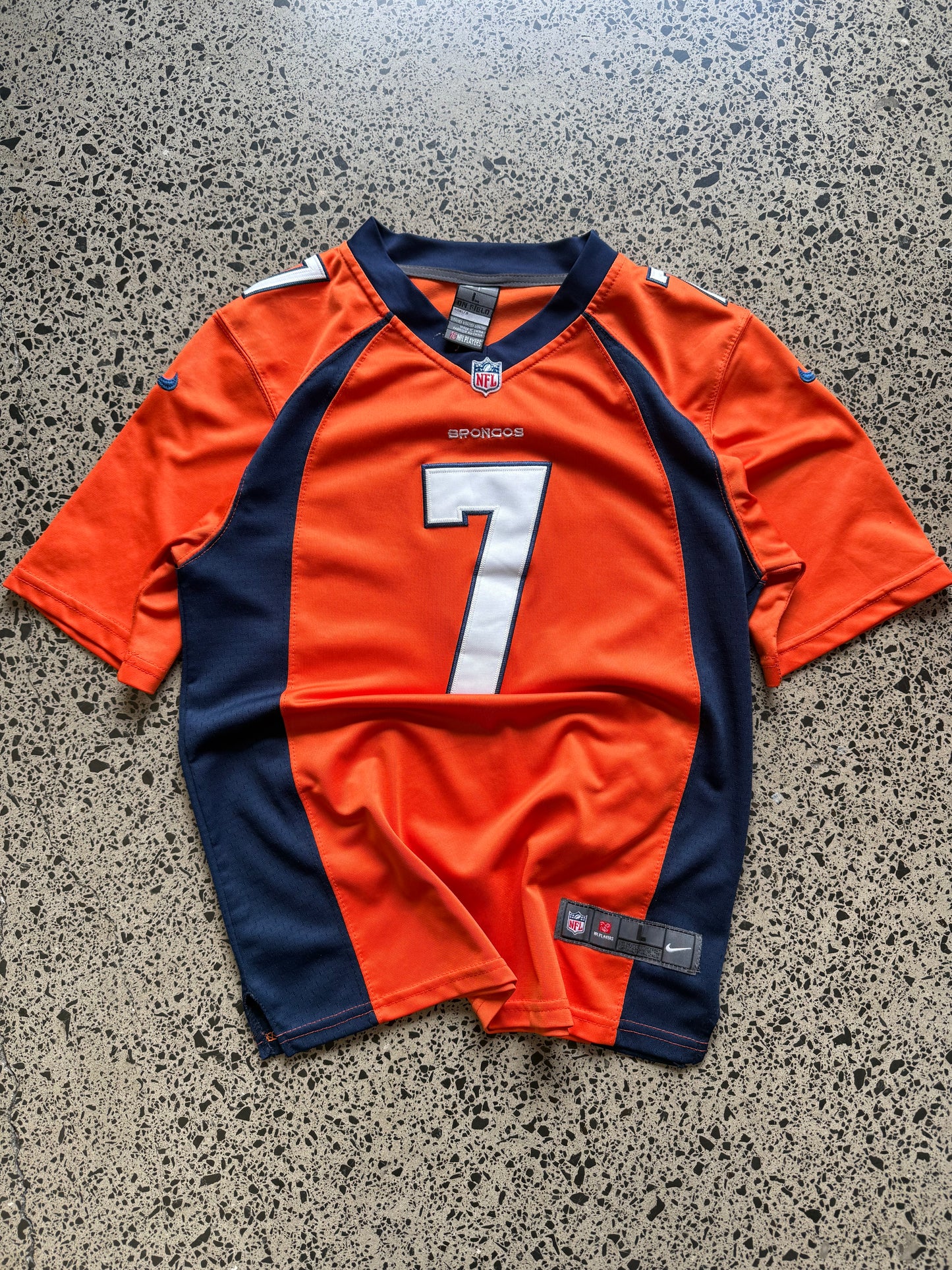Denver Broncos John Elway NFL jersey size L laid on polished concrete background — bright orange with navy and white detailing and Broncos logo.