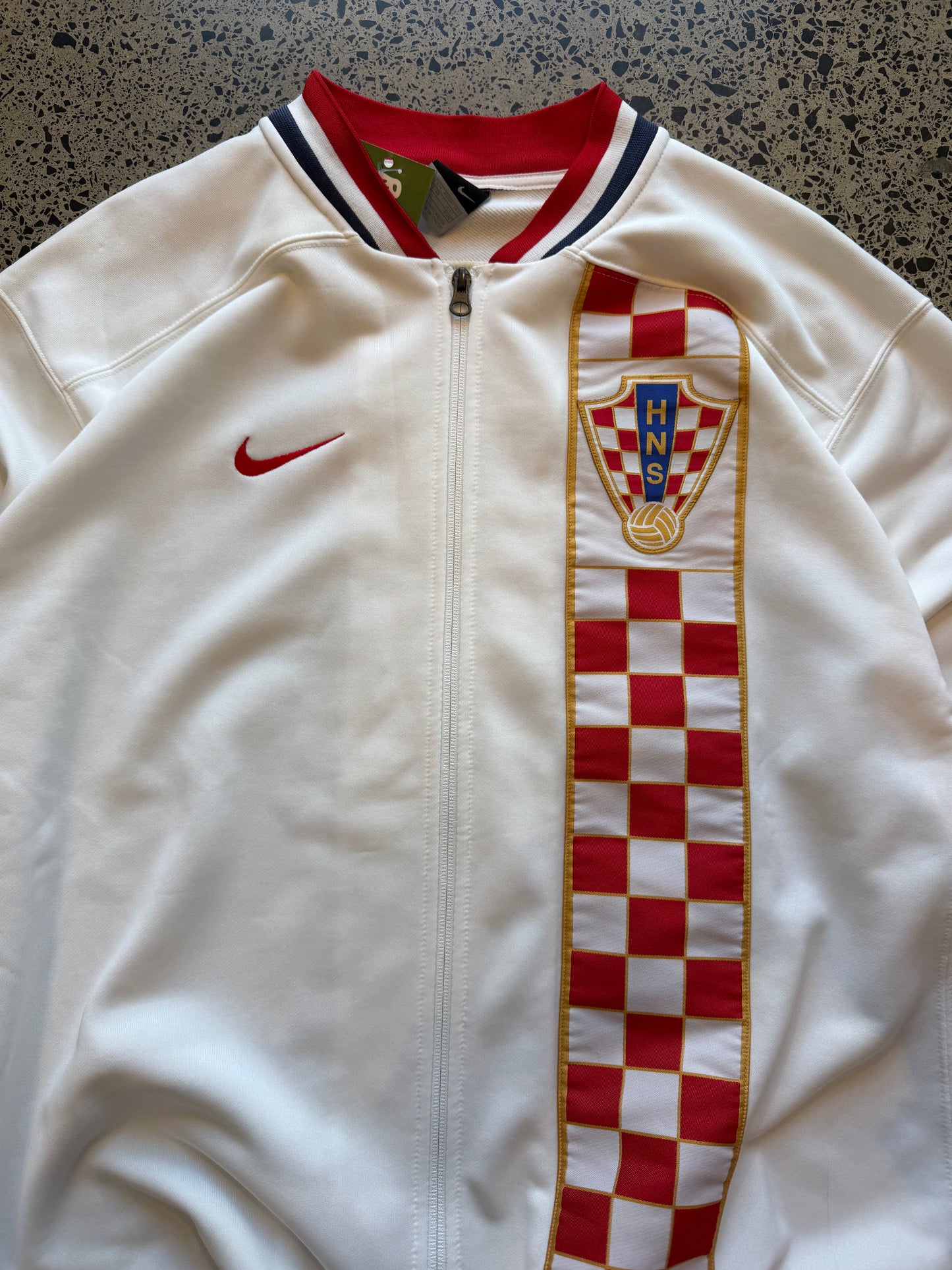 Croatia Nike red and white zip-up football jumper, size XXL, laid on polished concrete background — ¼-zip pullover with team crest and swoosh.