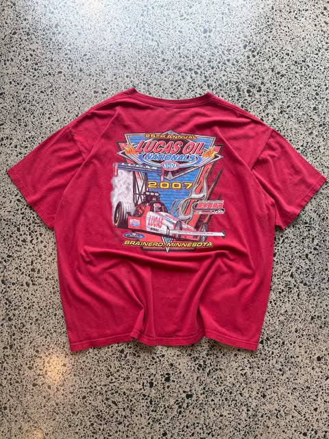 2007 Lucas Oil graphic T-shirt laid on a polished concrete background featuring bold motorsport logo artwork.