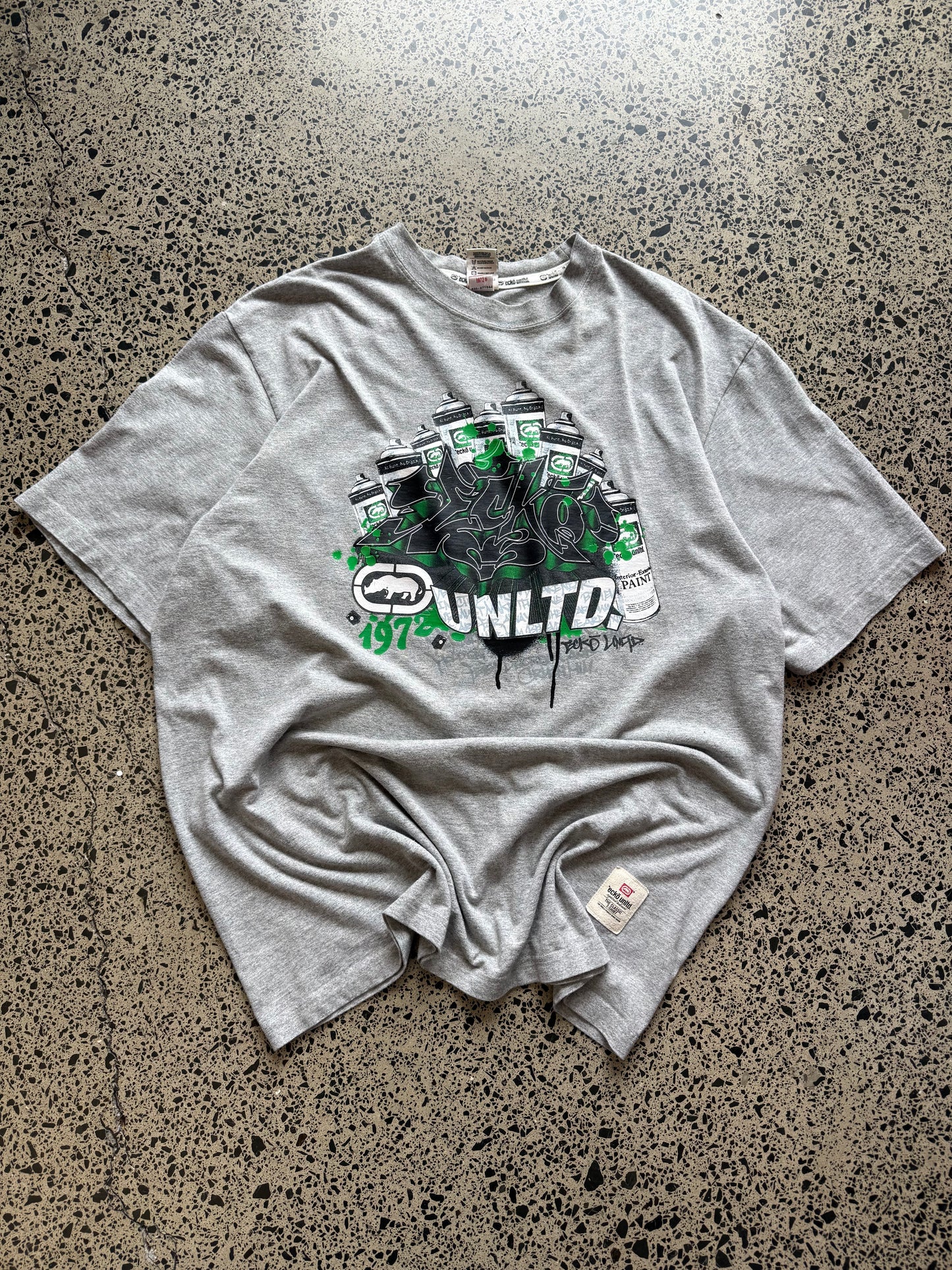 Ecko Unltd grey graffiti T-shirt, size 2XL, laid on polished concrete background — Y2K streetwear logo graphic on soft cotton.