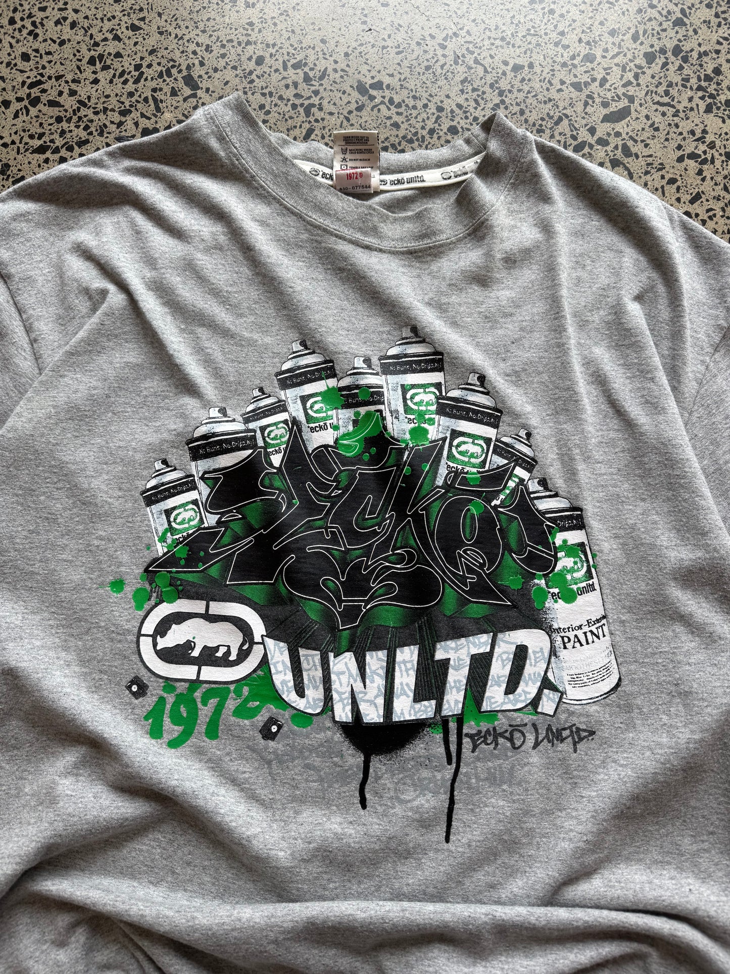 Ecko Unltd grey graffiti T-shirt, size 2XL, laid on polished concrete background — Y2K streetwear logo graphic on soft cotton.