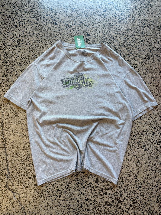 Grey early 2000s Quiksilver graphic t-shirt with chest and back logo print, size L, laid flat on a polished concrete background