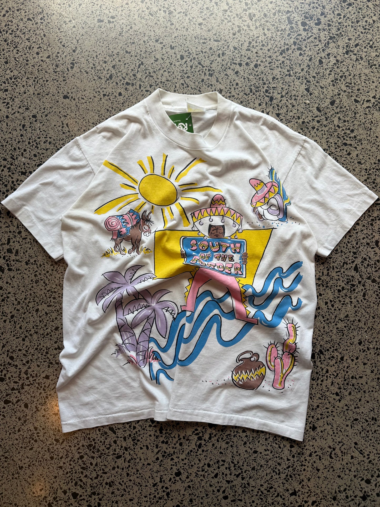90s South of the Border graphic T-shirt, size L, laid on a polished concrete background with colourful vintage print.