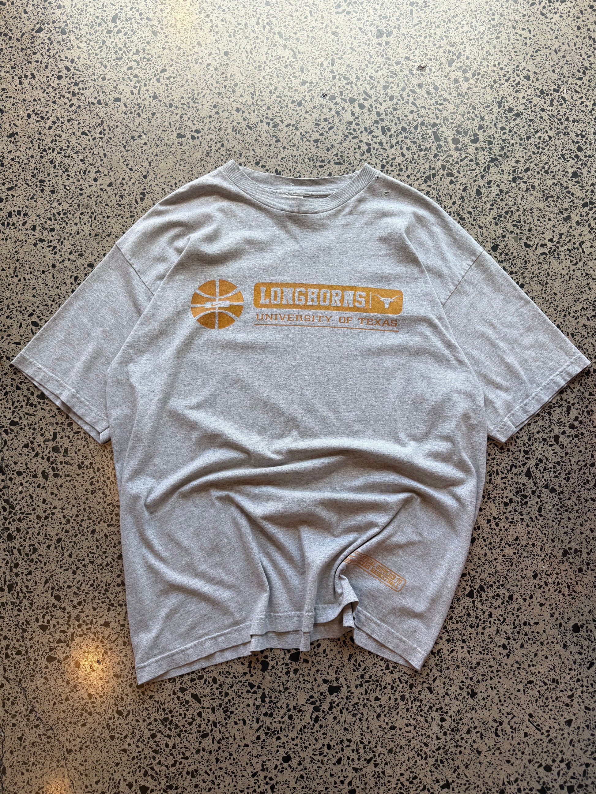 90s University of Texas Longhorns T-shirt, size 2XL, laid on polished concrete background, vintage collegiate Longhorns graphic on soft cotton.