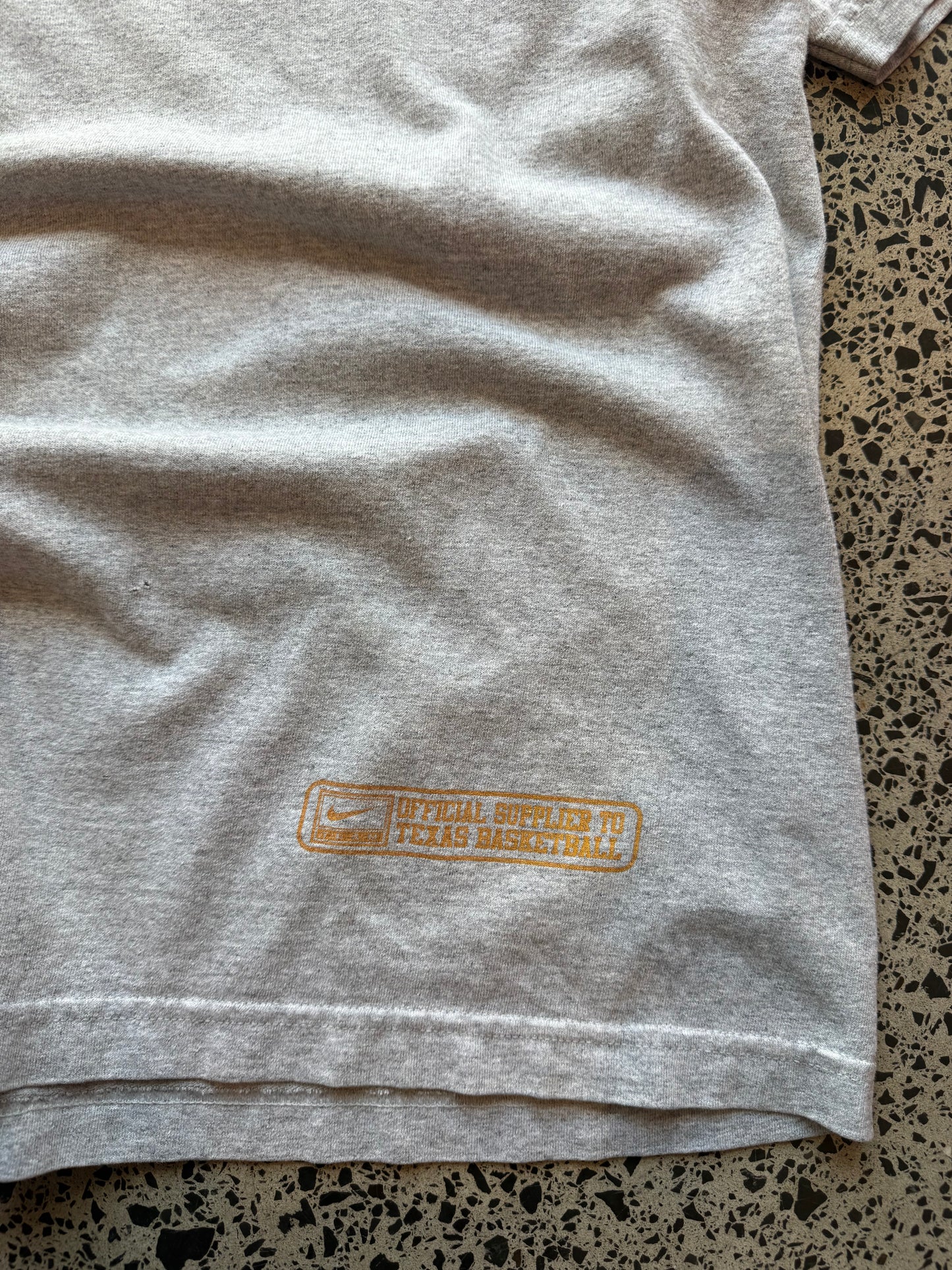 90s University of Texas Longhorns T-shirt, size 2XL, laid on polished concrete background, vintage collegiate Longhorns graphic on soft cotton.