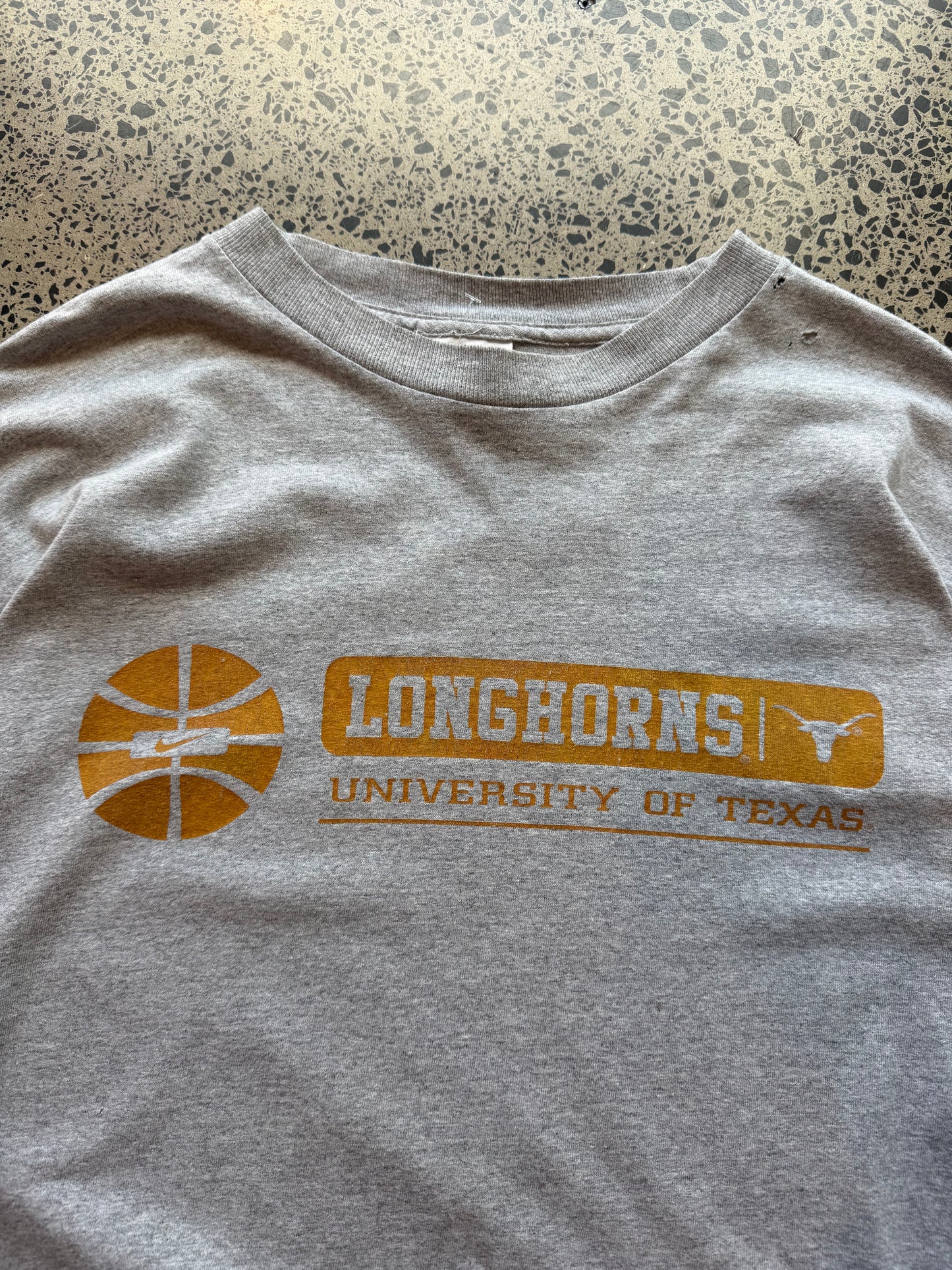 90s University of Texas Longhorns T-shirt, size 2XL, laid on polished concrete background, vintage collegiate Longhorns graphic on soft cotton.