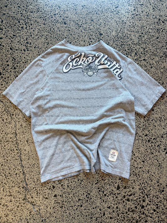 Grey Y2K Ecko Unltd graphic t-shirt with bold chest print, size M, laid flat on a polished concrete background