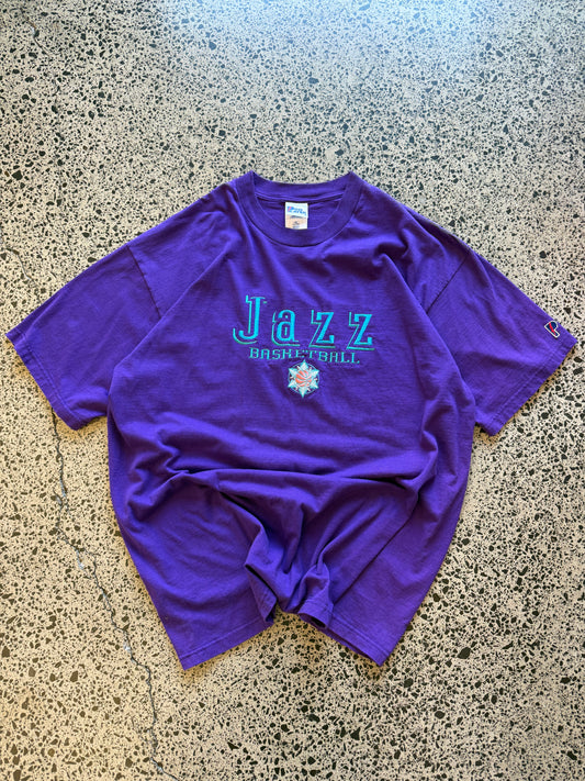 Vintage 90s Utah Jazz NBA t-shirt on a purple base and blue team logos and graphics embroidered across the front.  Size 2XL. Oversized basketball streetwear