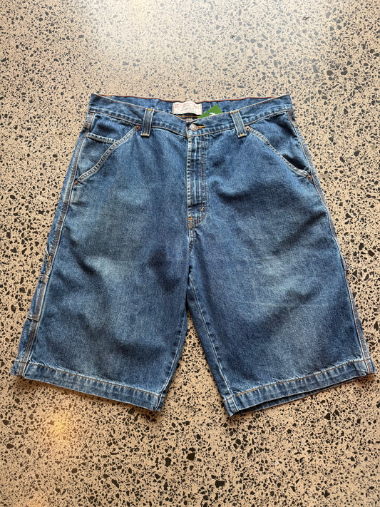 Levi strauss dark blue wash denim jorts, size 32W, laid on polished concrete background. Knee cut with classic stitching and soft wash