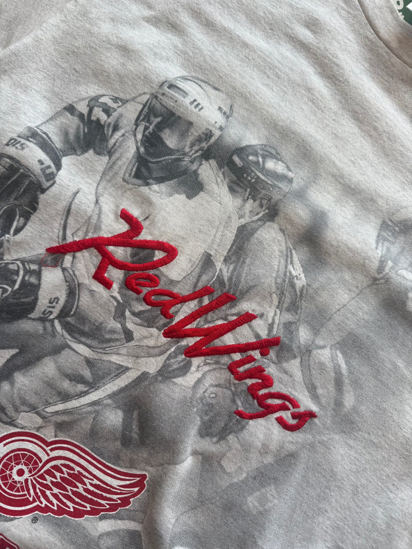 90s Detroit Red Wings NHL T-shirt, red, size M, laid on polished concrete background — vintage hockey graphic on soft cotton.