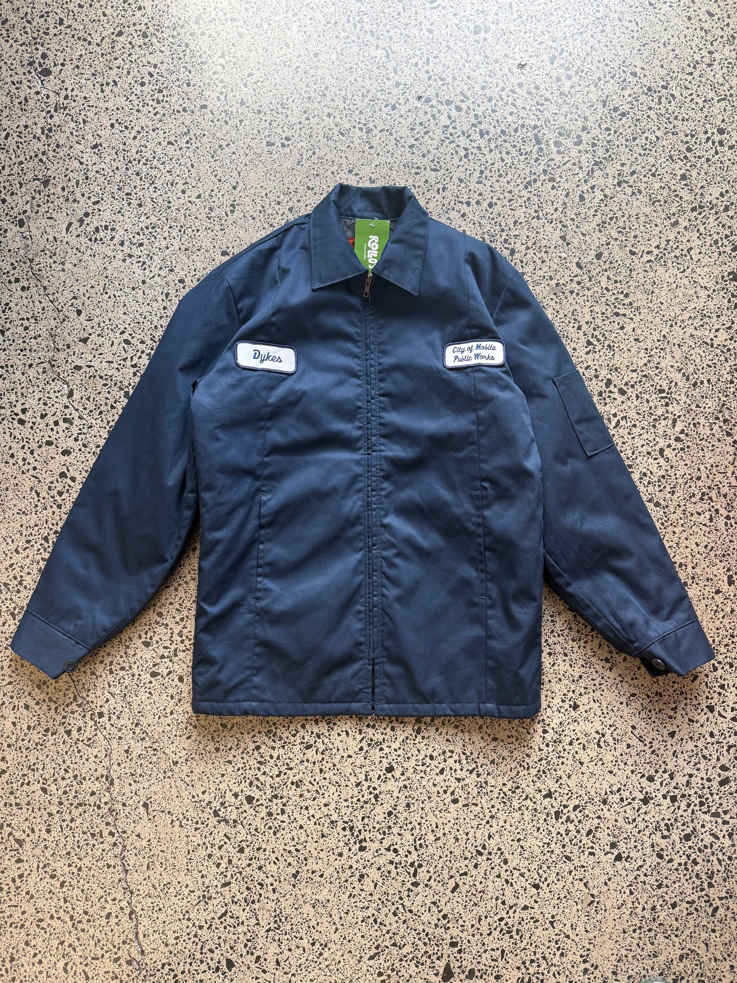 Red Kap workwear zipper jacket size Small Regular laid on polished concrete background — dark navy with zip front and pockets.