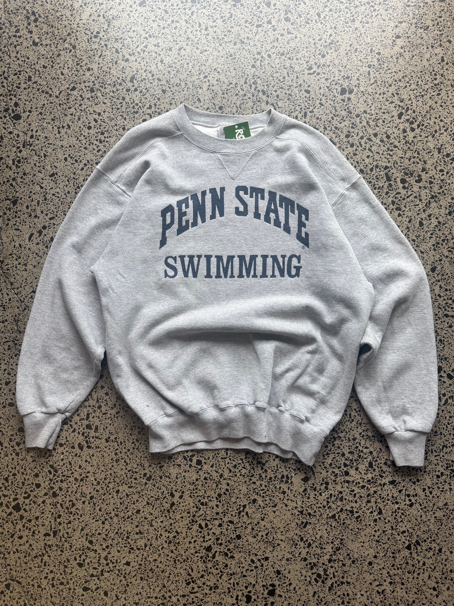 90s Penn State University crewneck jumper size M laid flat on polished concrete background, vintage college sweatshirt with bold lettering and classic fit.