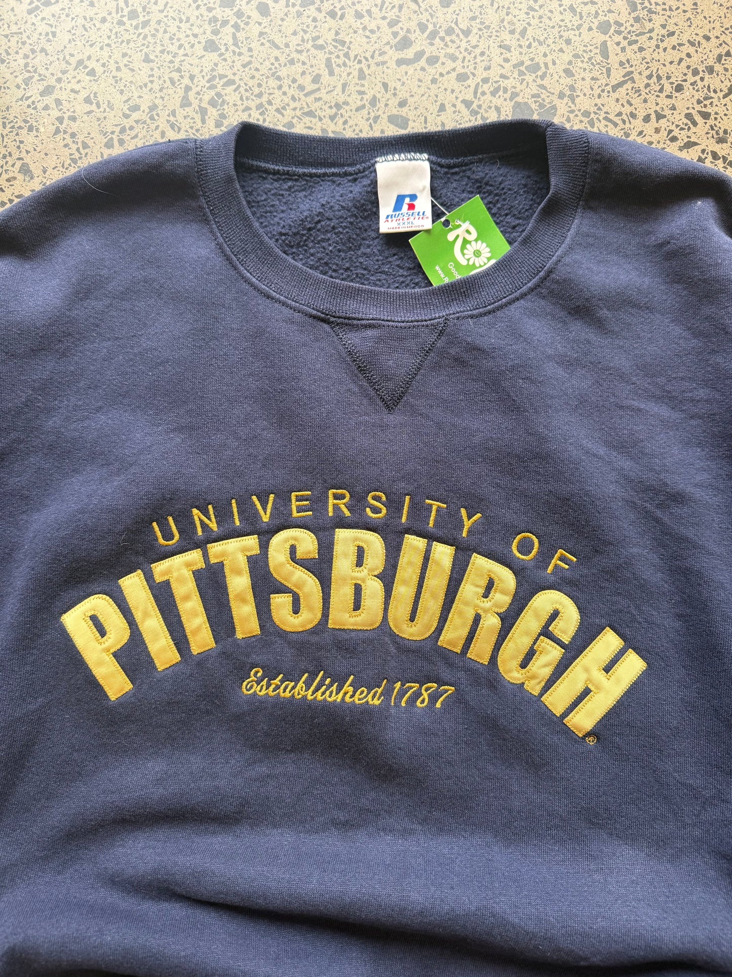 90s University of Pittsburgh crewneck jumper size 3XL laid flat on polished concrete background, vintage college sweatshirt with bold lettering and oversized fit.