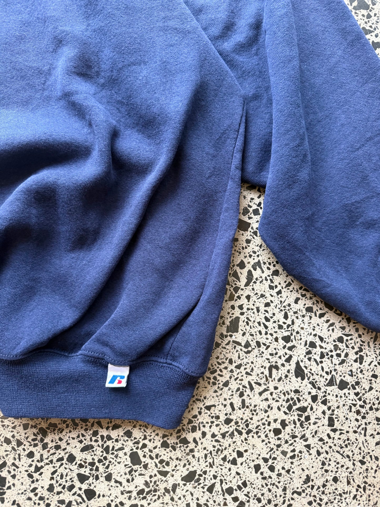 90s University of Pittsburgh crewneck jumper size 3XL laid flat on polished concrete background, vintage college sweatshirt with bold lettering and oversized fit.