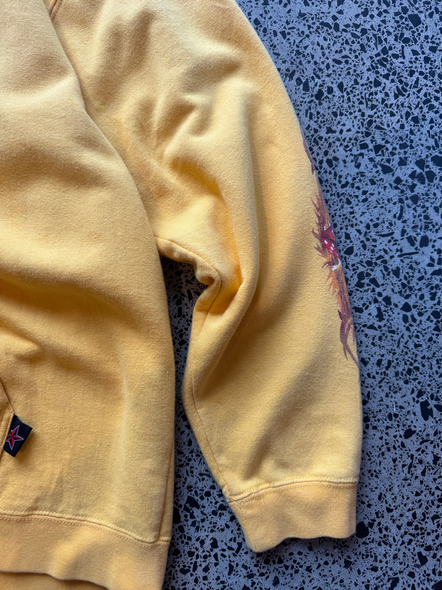 Y2K Top Heavy skull and bones hoodie XL laid flat on polished concrete background, vintage streetwear hoodie with bold graphic print and relaxed fit.