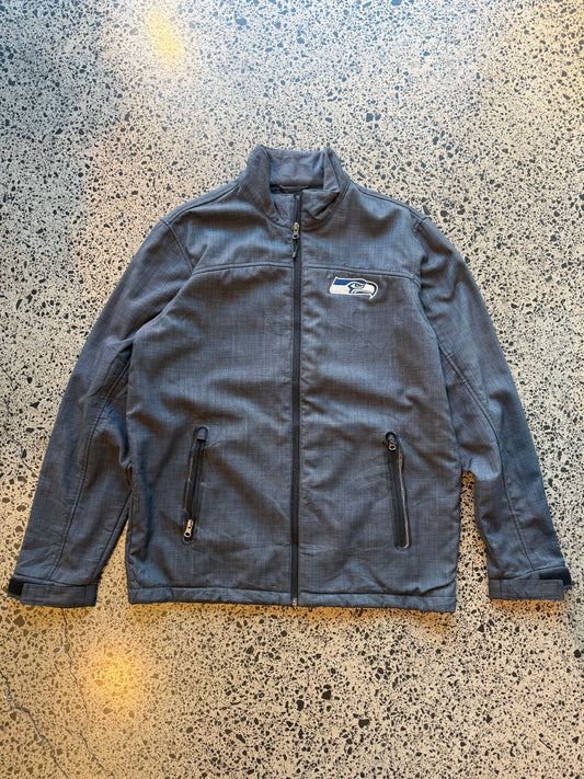 Seattle Seahawks NFL soft shell jacket size M laid flat on polished concrete background, lightweight sportswear jacket with subtle team branding and clean fit.