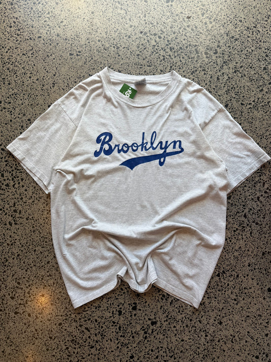 90s grey Brooklyn graphic T-shirt, size 2XL, laid on polished concrete background soft vintage cotton with bold NYC lettering.