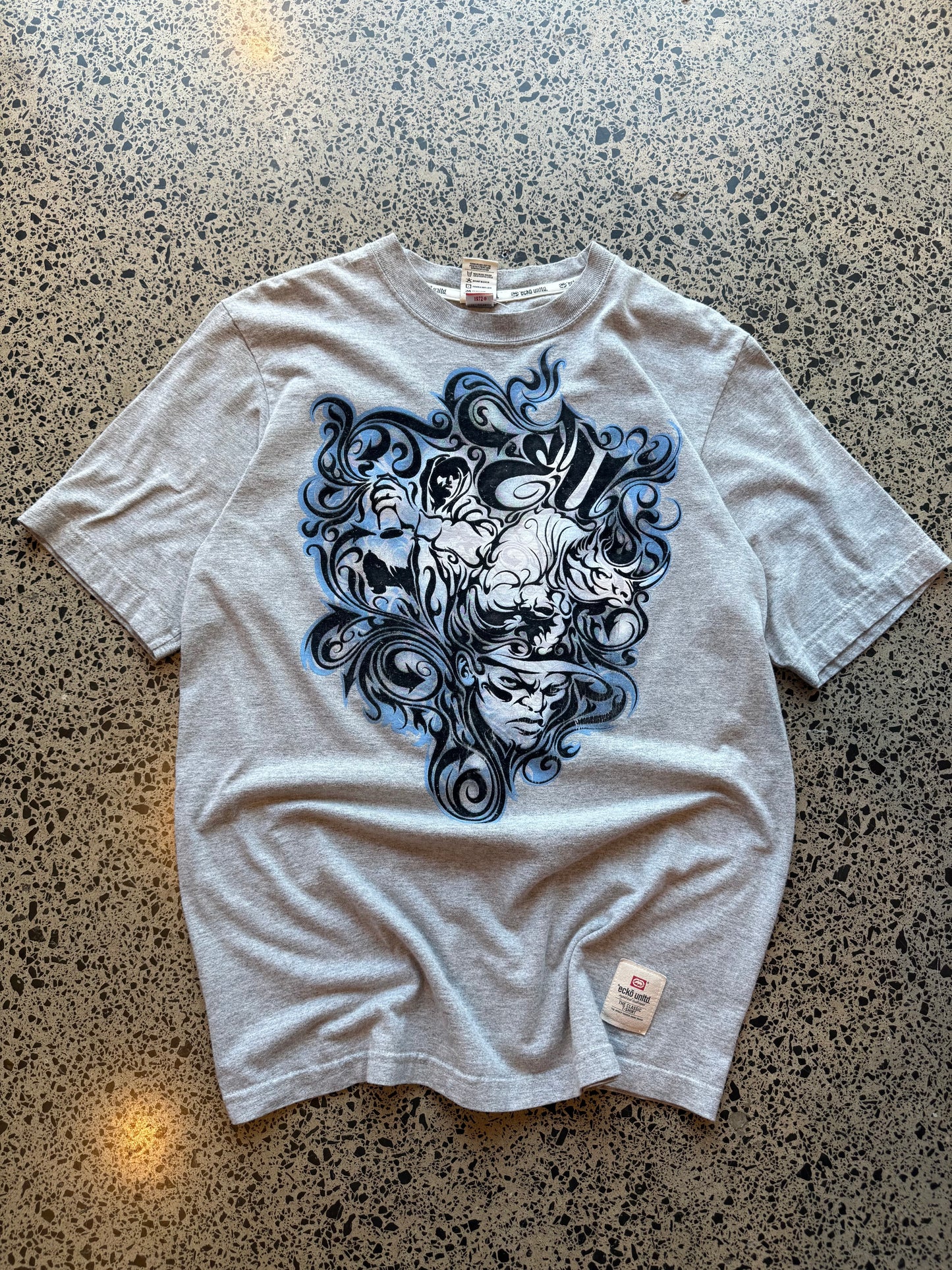 Ecko Unltd black graphic T-shirt in size L laid on a polished concrete background with large rhino logo on the front.