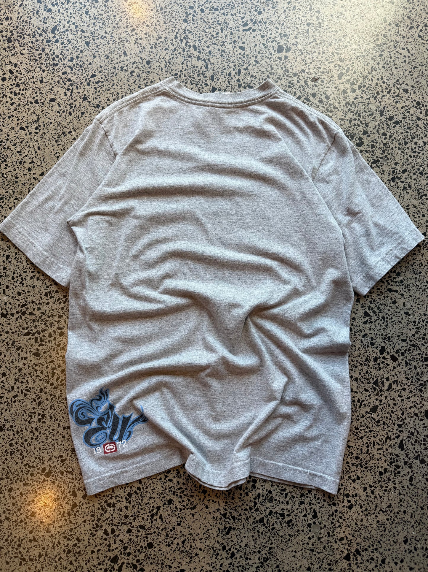 Ecko Unltd black graphic T-shirt in size L laid on a polished concrete background with large rhino logo on the front.