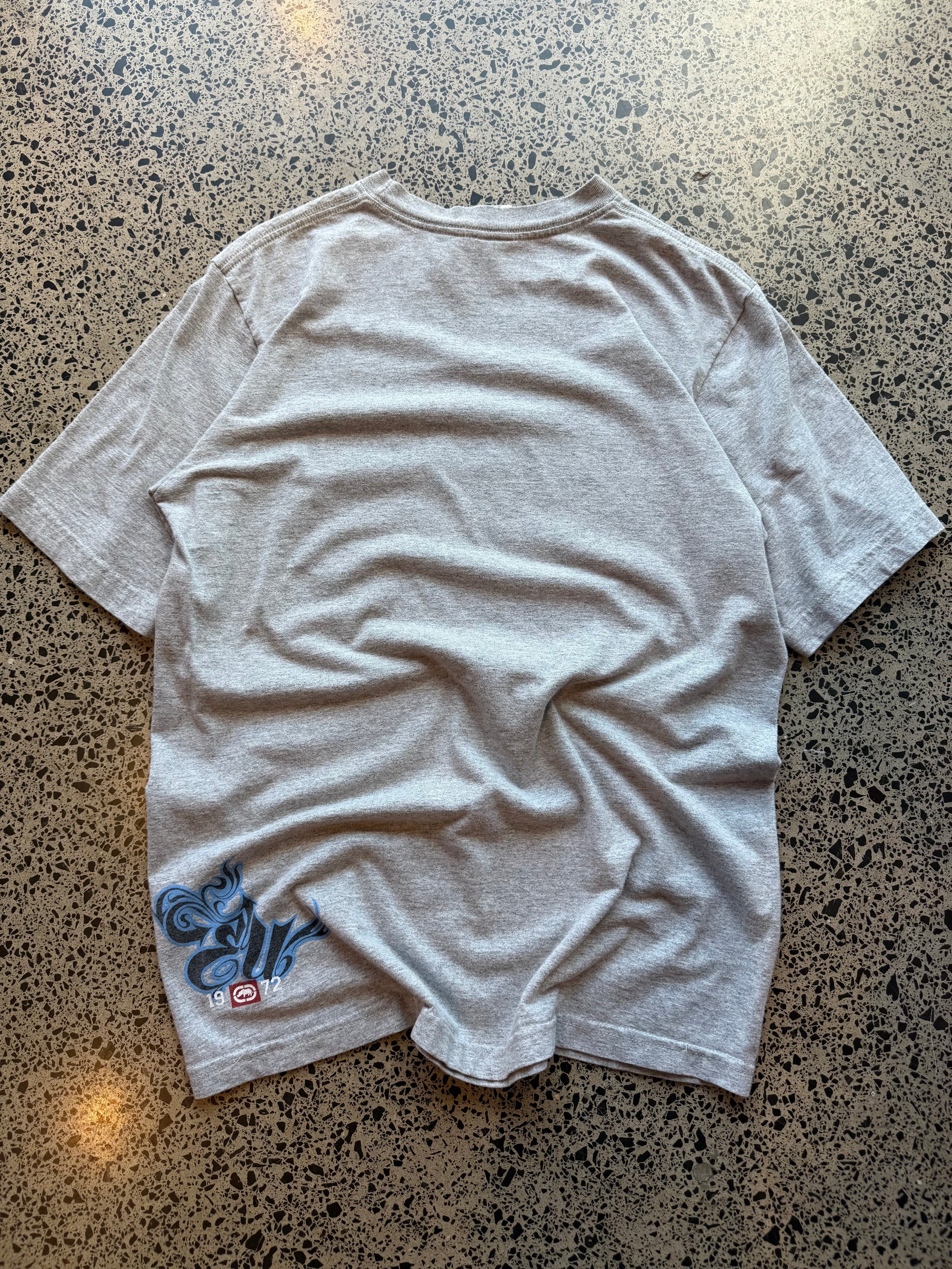 Ecko Unltd black graphic T-shirt in size L laid on a polished concrete background with large rhino logo on the front.