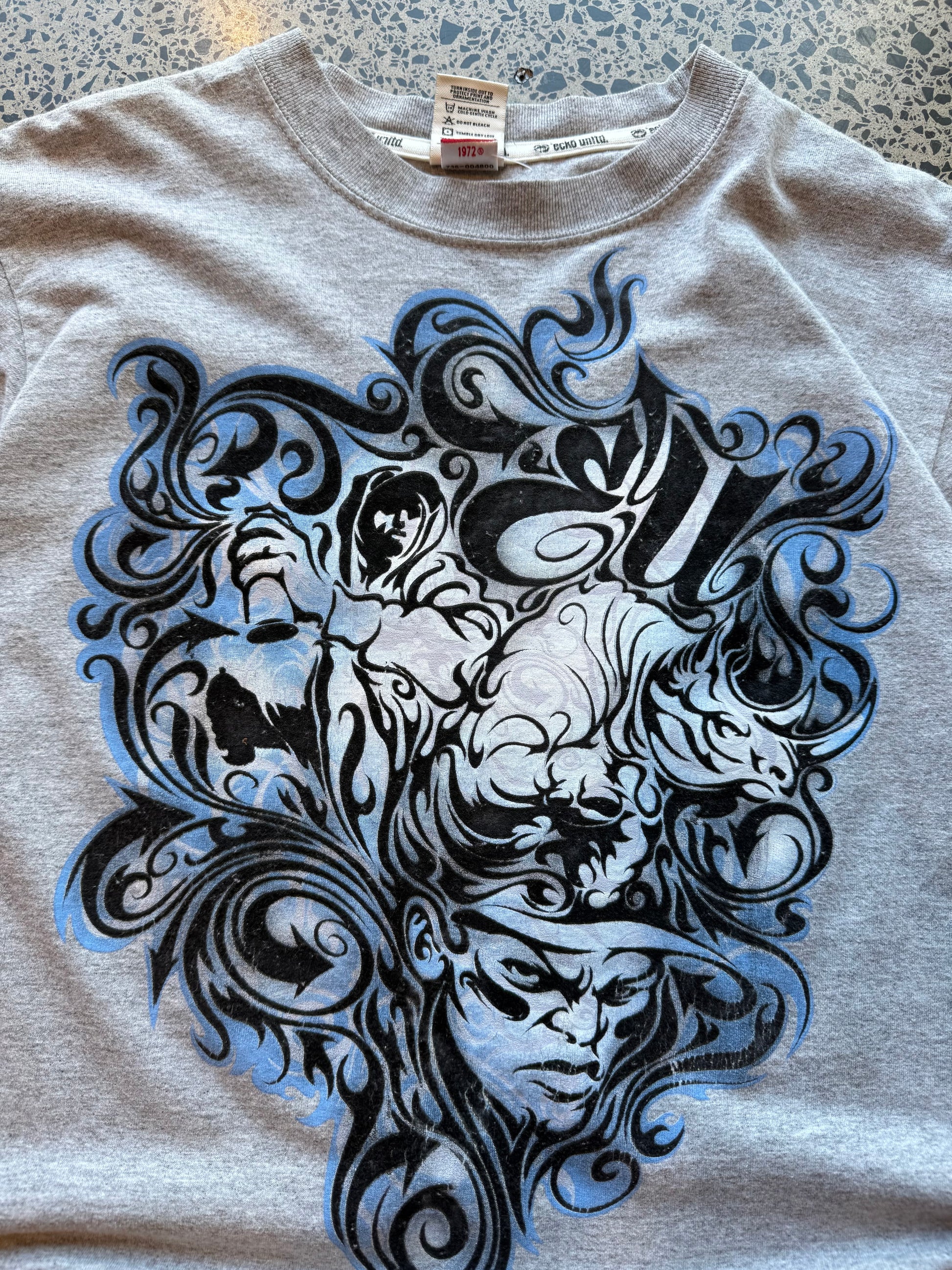 Ecko Unltd black graphic T-shirt in size L laid on a polished concrete background with large rhino logo on the front.