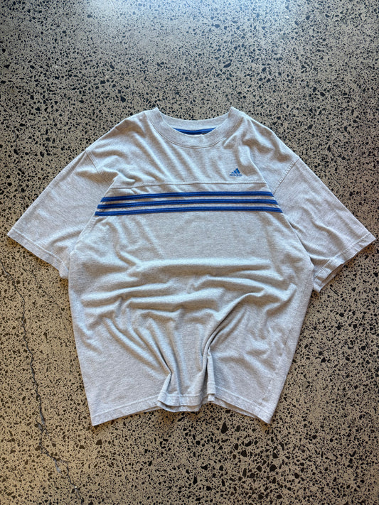 90s vintage Adidas essential T-shirt size XL laid on polished concrete background — black tee with Adidas logo.
