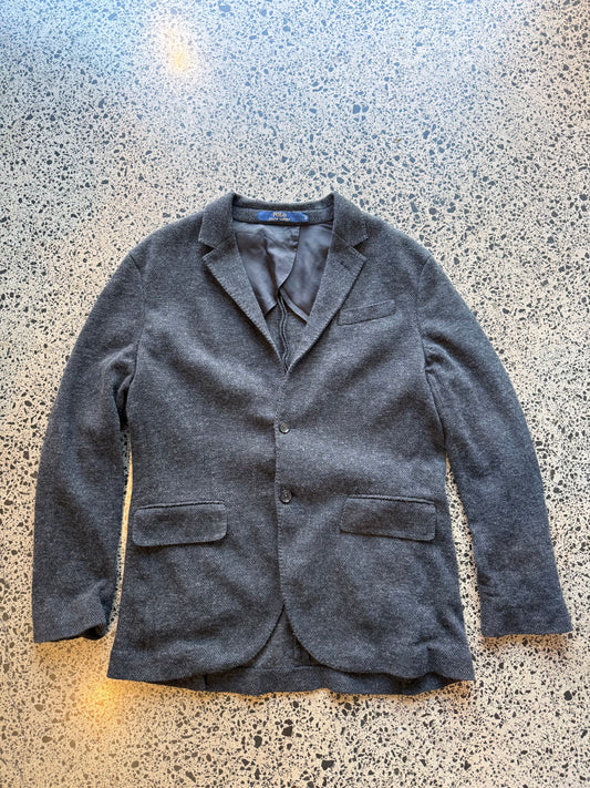 Ralph Lauren herringbone 100 percent wool blazer jacket laid flat on polished concrete background, classic tailored jacket with textured pattern and clean fit.