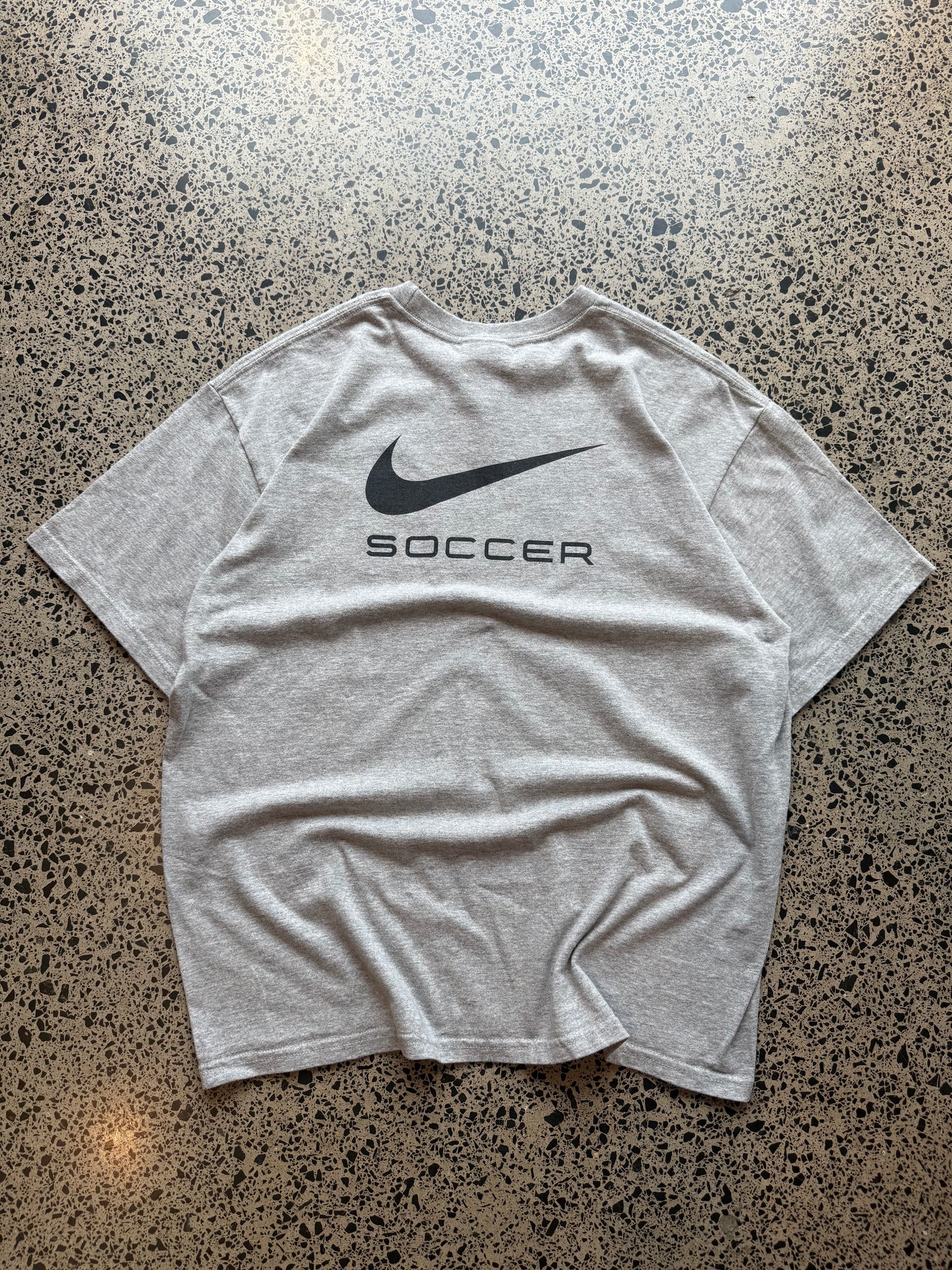 2000s Nike Abby Wambach Soccer Camp T-shirt in size M laid on a polished concrete background featuring U.S. women’s soccer camp graphic.