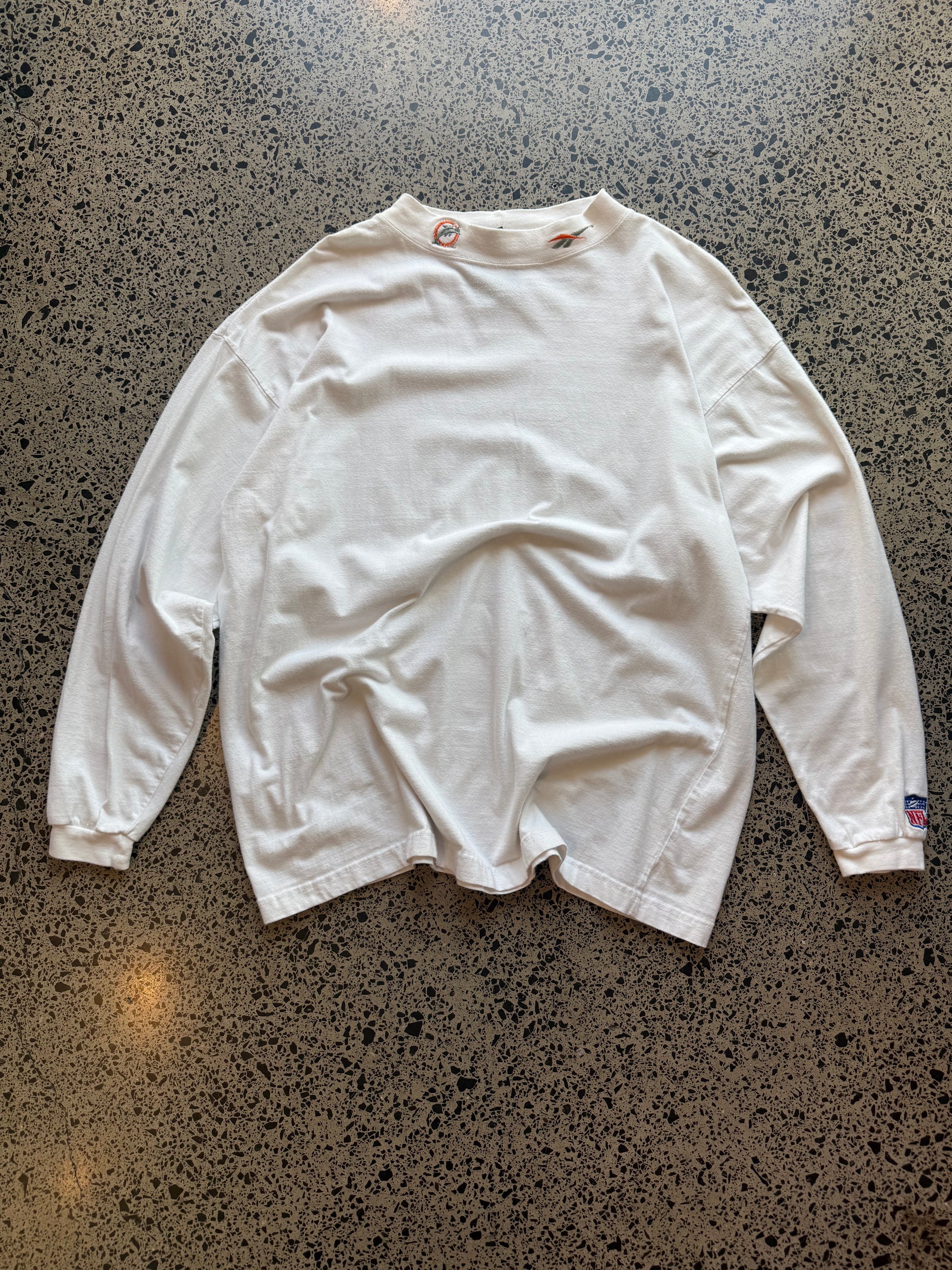 90s Miami Dolphins NFL long sleeve shirt 2XL laid flat on polished concrete background, vintage football tee with team colors and bold graphics.