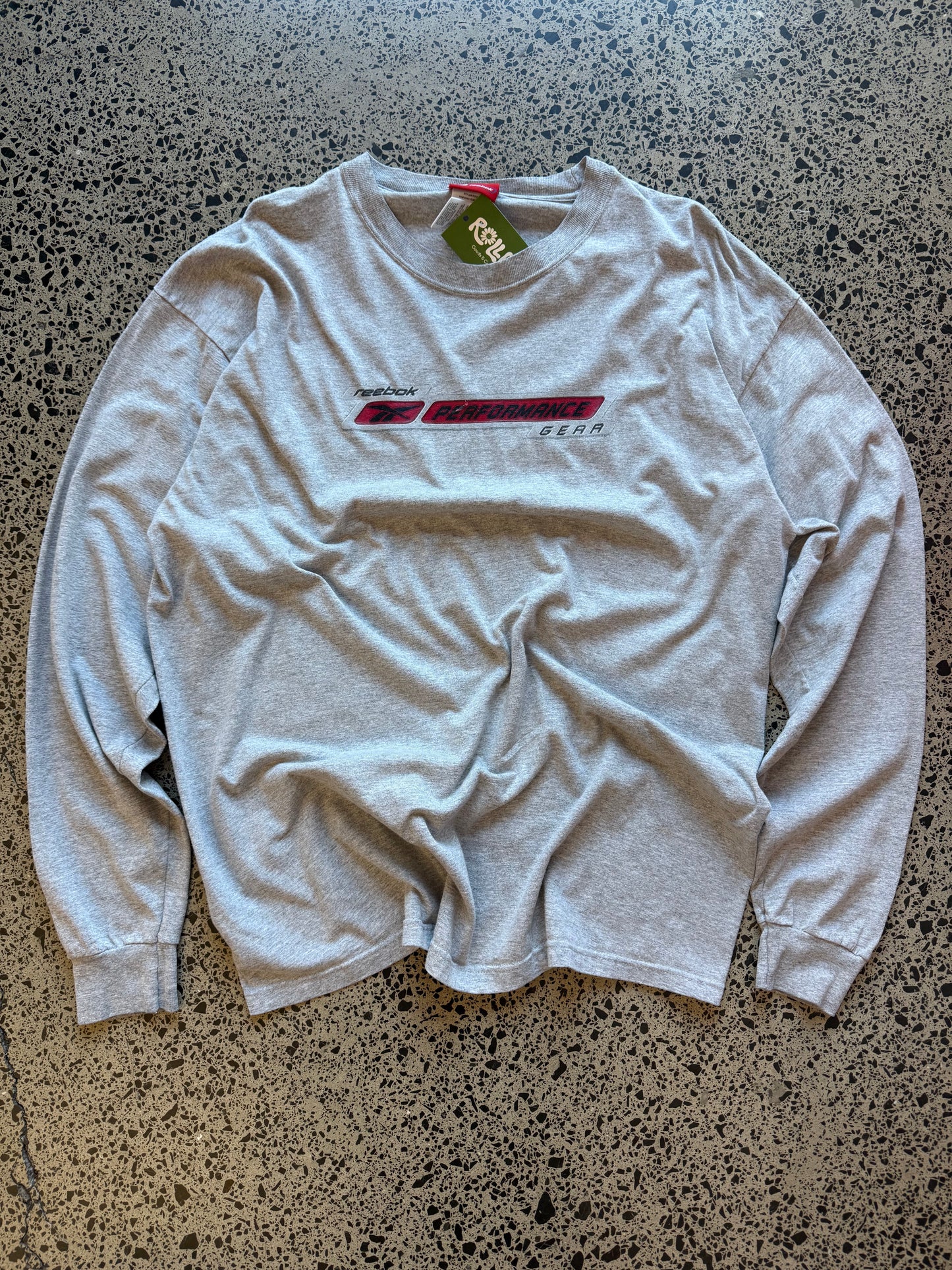 Early 2000s Reebok long sleeve T-shirt size L laid on polished concrete background — black with bold Reebok logo.